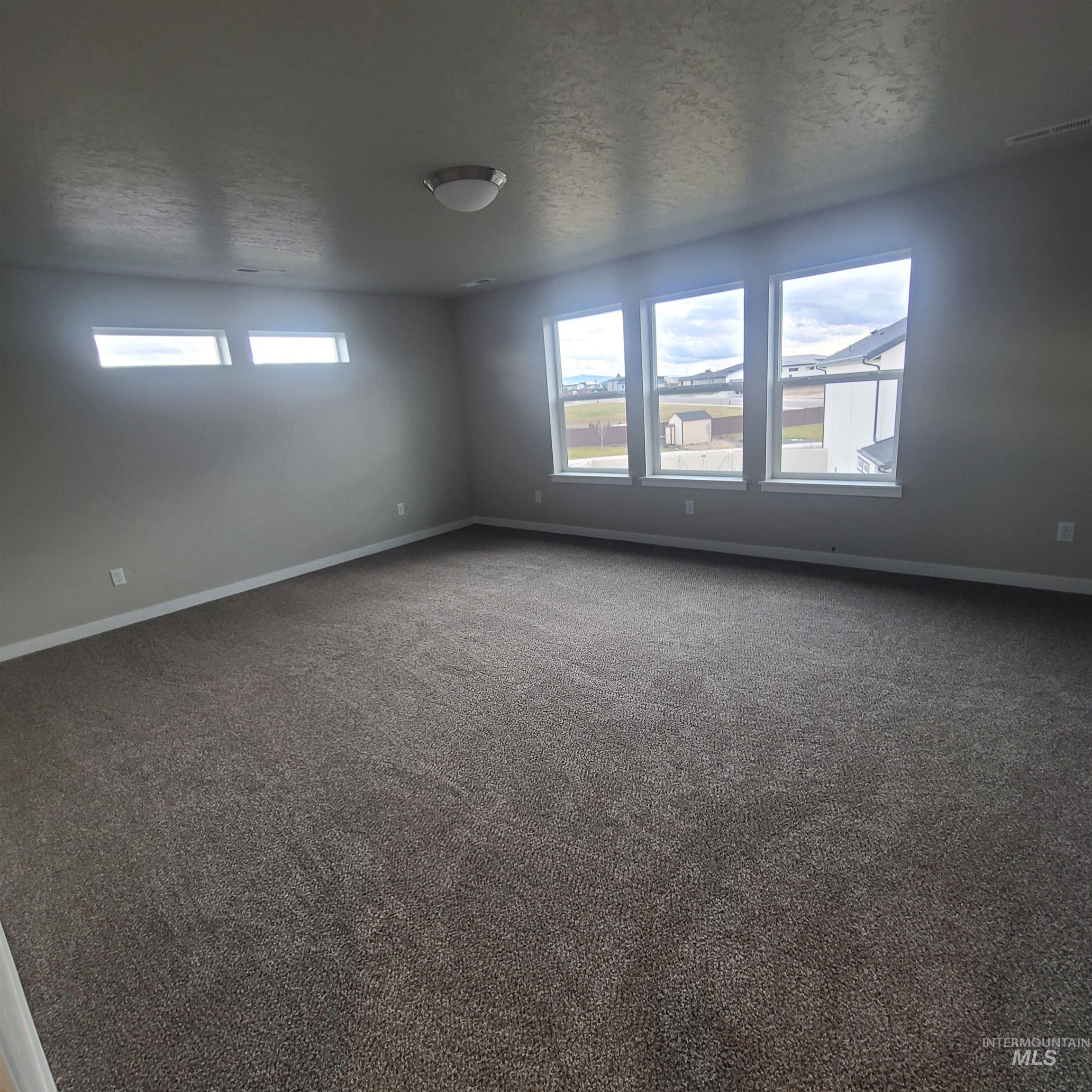 Carpeted empty room with a textured ceiling