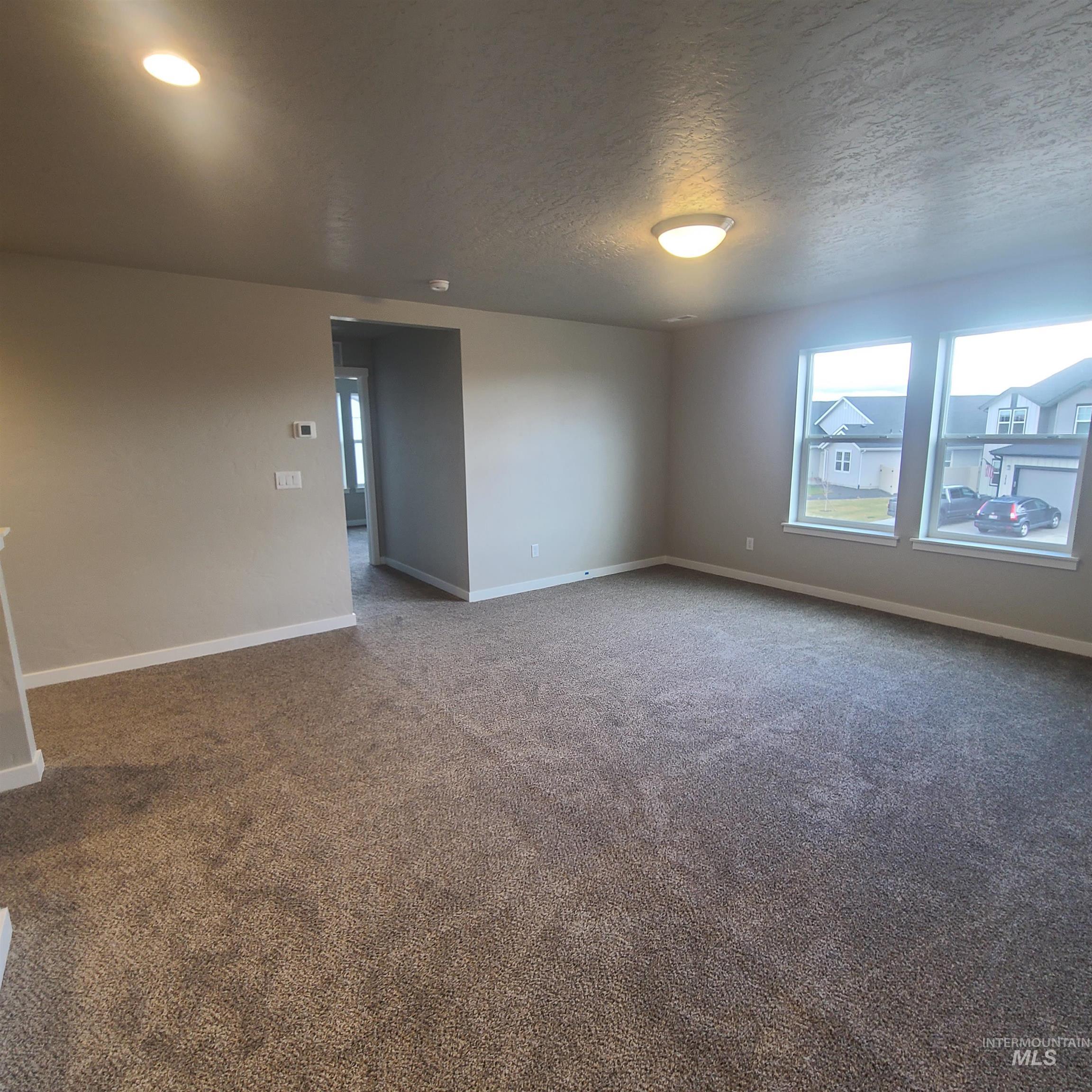 Empty room featuring dark colored carpet and a textured ceiling