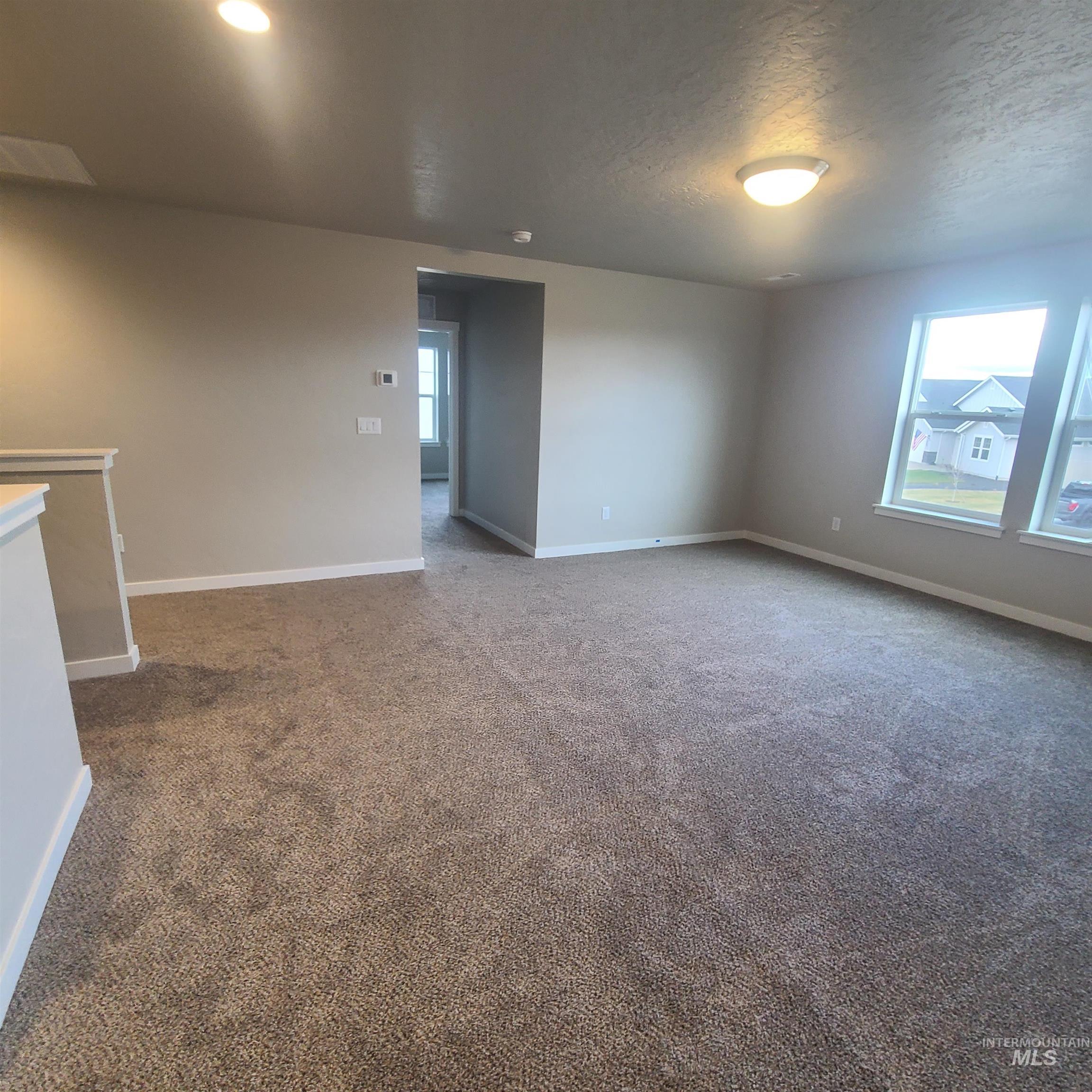 Unfurnished room featuring dark colored carpet and a textured ceiling