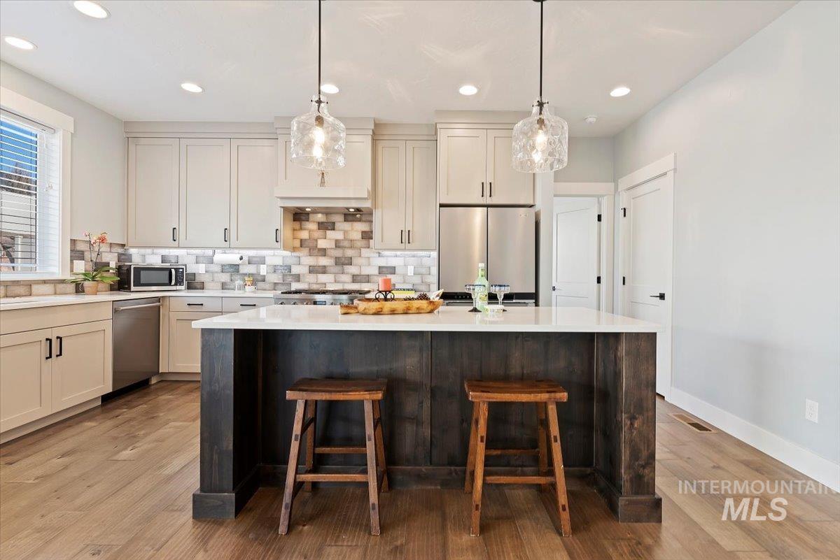 Kitchen with tasteful backsplash, stainless steel appliances, a kitchen island, pendant lighting, and recessed lighting