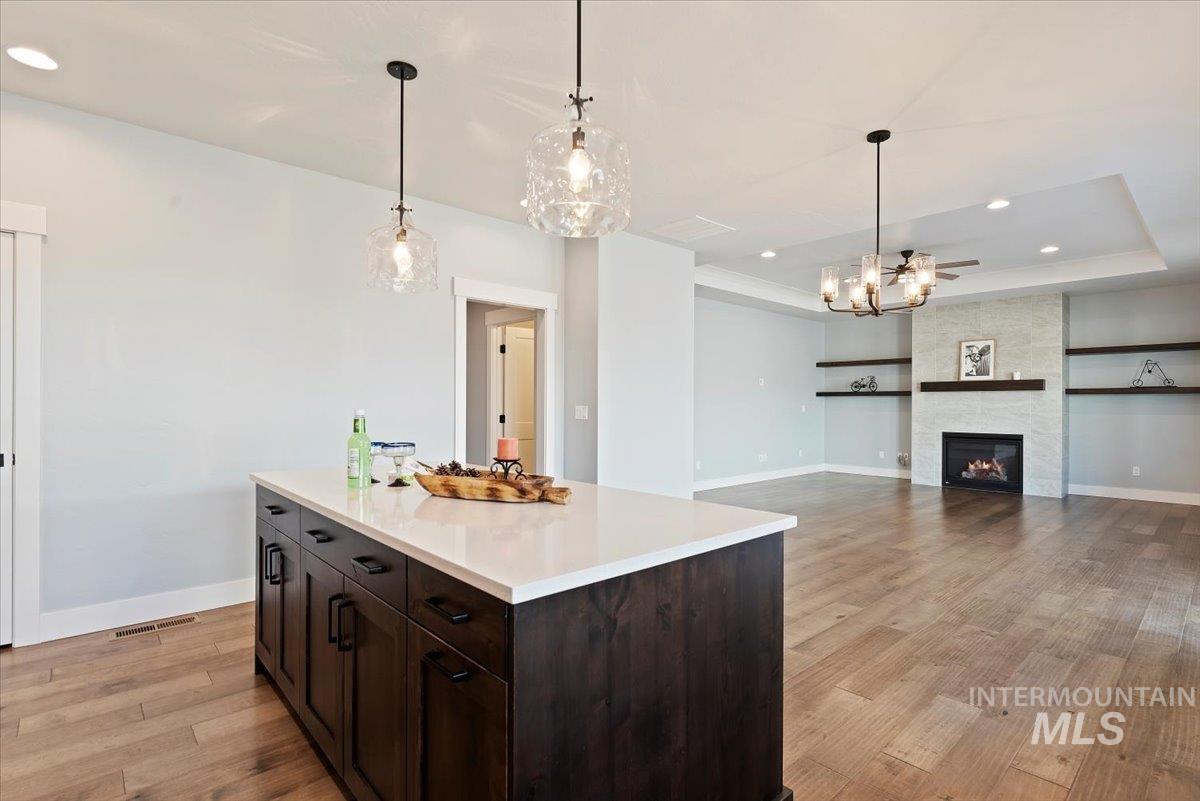 Kitchen featuring dark brown cabinets, recessed lighting, light wood-style floors, a raised ceiling, and a kitchen island