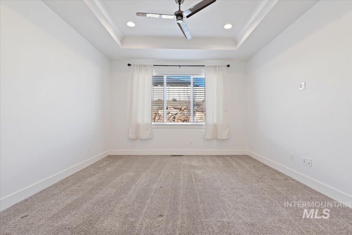 Unfurnished room with light carpet, a tray ceiling, recessed lighting, a ceiling fan, and crown molding