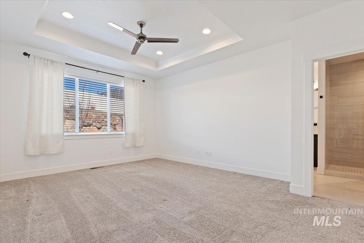 Spare room featuring a raised ceiling, light carpet, recessed lighting, and ceiling fan
