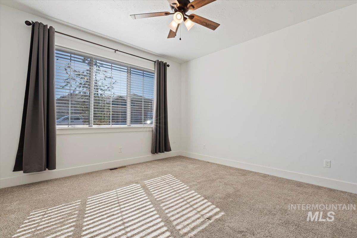 Empty room featuring light colored carpet and a ceiling fan