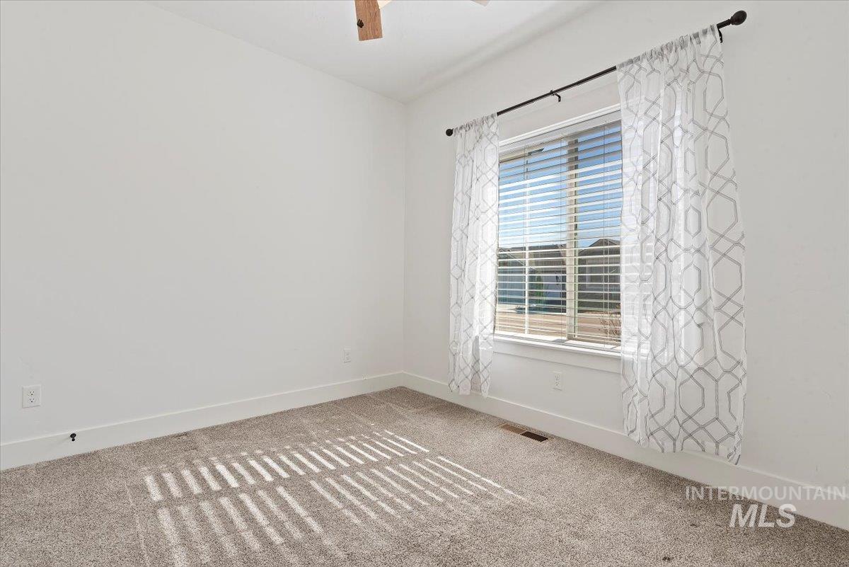 Carpeted spare room featuring baseboards and a ceiling fan