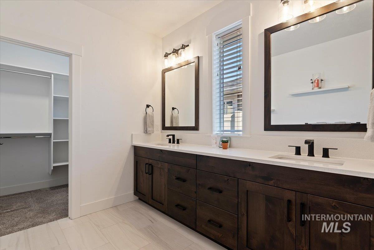 Full bathroom with double vanity and a walk in closet