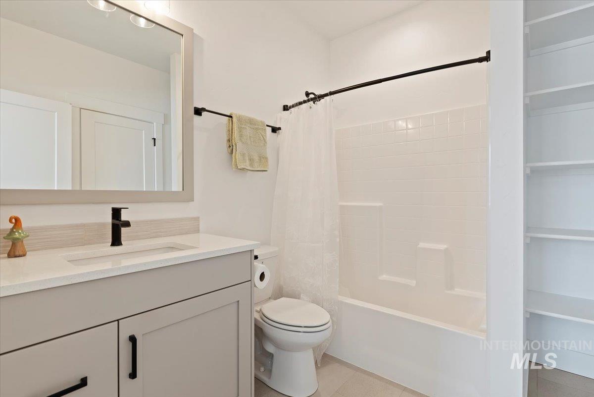 Bathroom with vanity, shower / tub combo with curtain, and light tile patterned floors