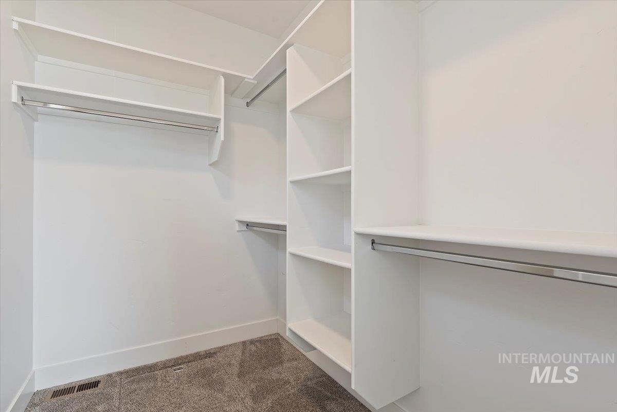 Walk in closet featuring dark carpet