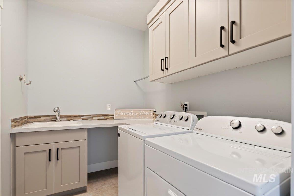 Laundry area featuring independent washer and dryer, cabinet space, and light tile patterned floors