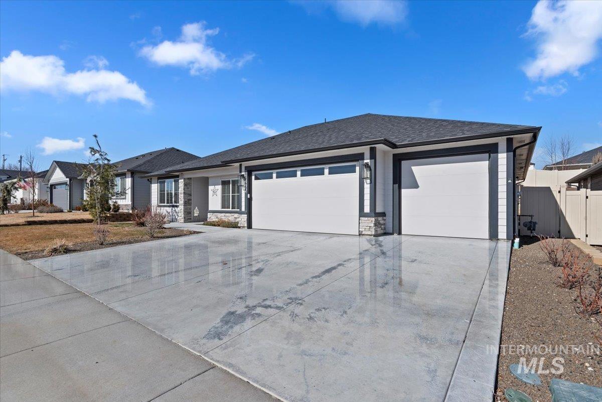 Prairie-style house featuring an attached garage, concrete driveway, stone siding, and a shingled roof