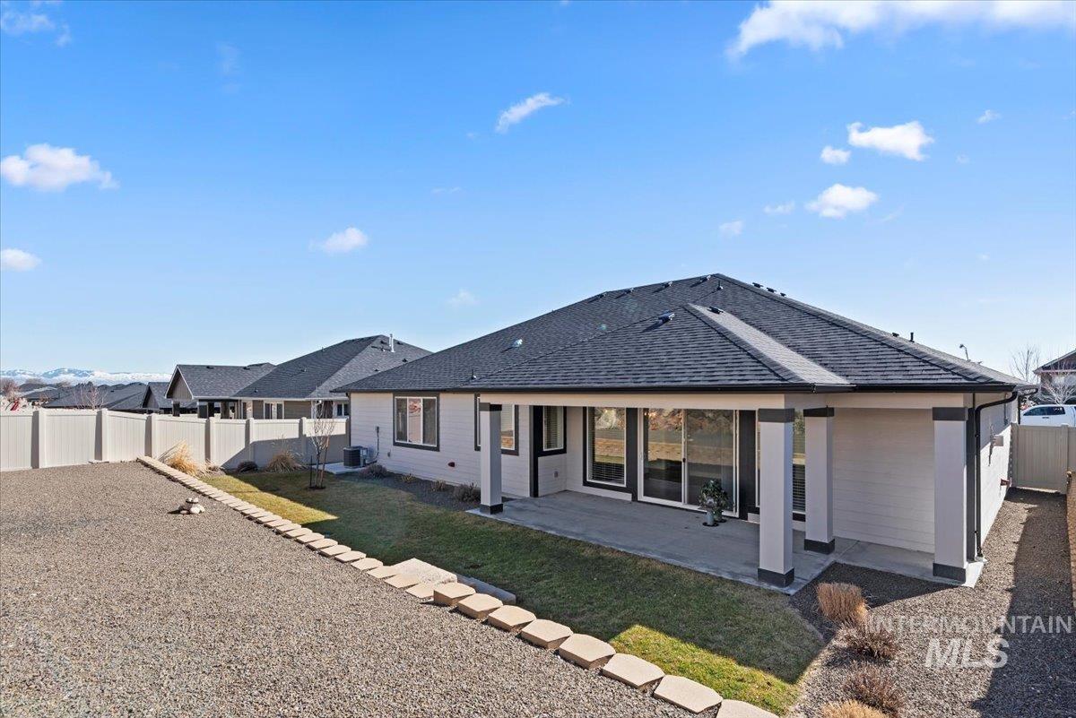 Back of property with a patio, a fenced backyard, and a shingled roof