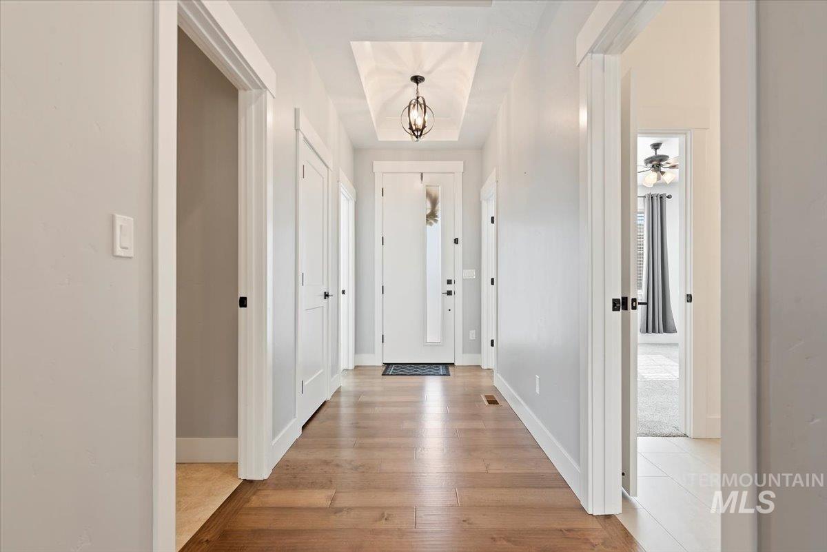 Foyer entrance featuring light wood-style flooring, a chandelier, and a raised ceiling