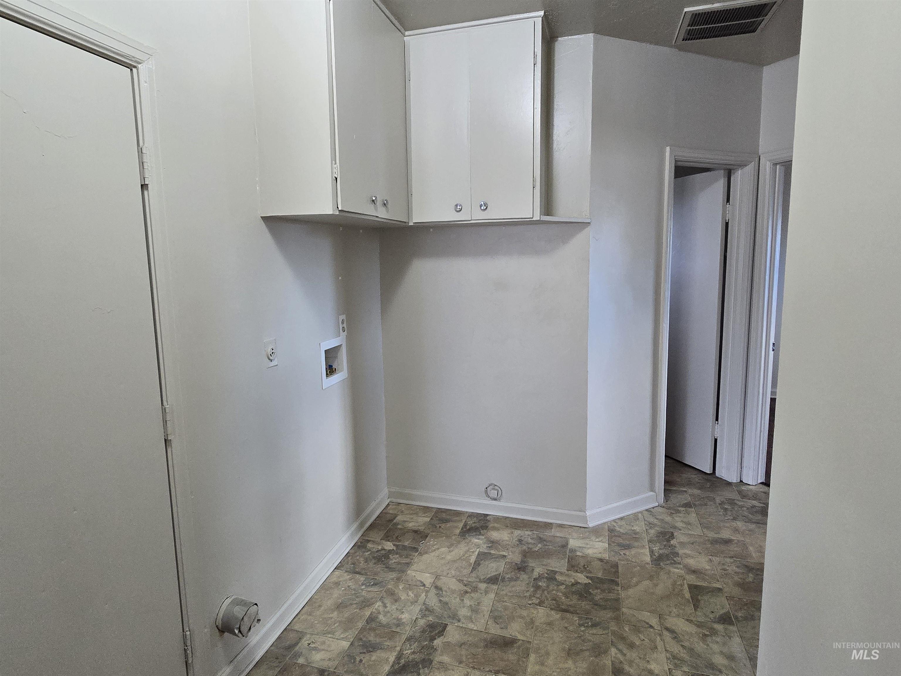Washroom featuring stone finish flooring and washer hookup