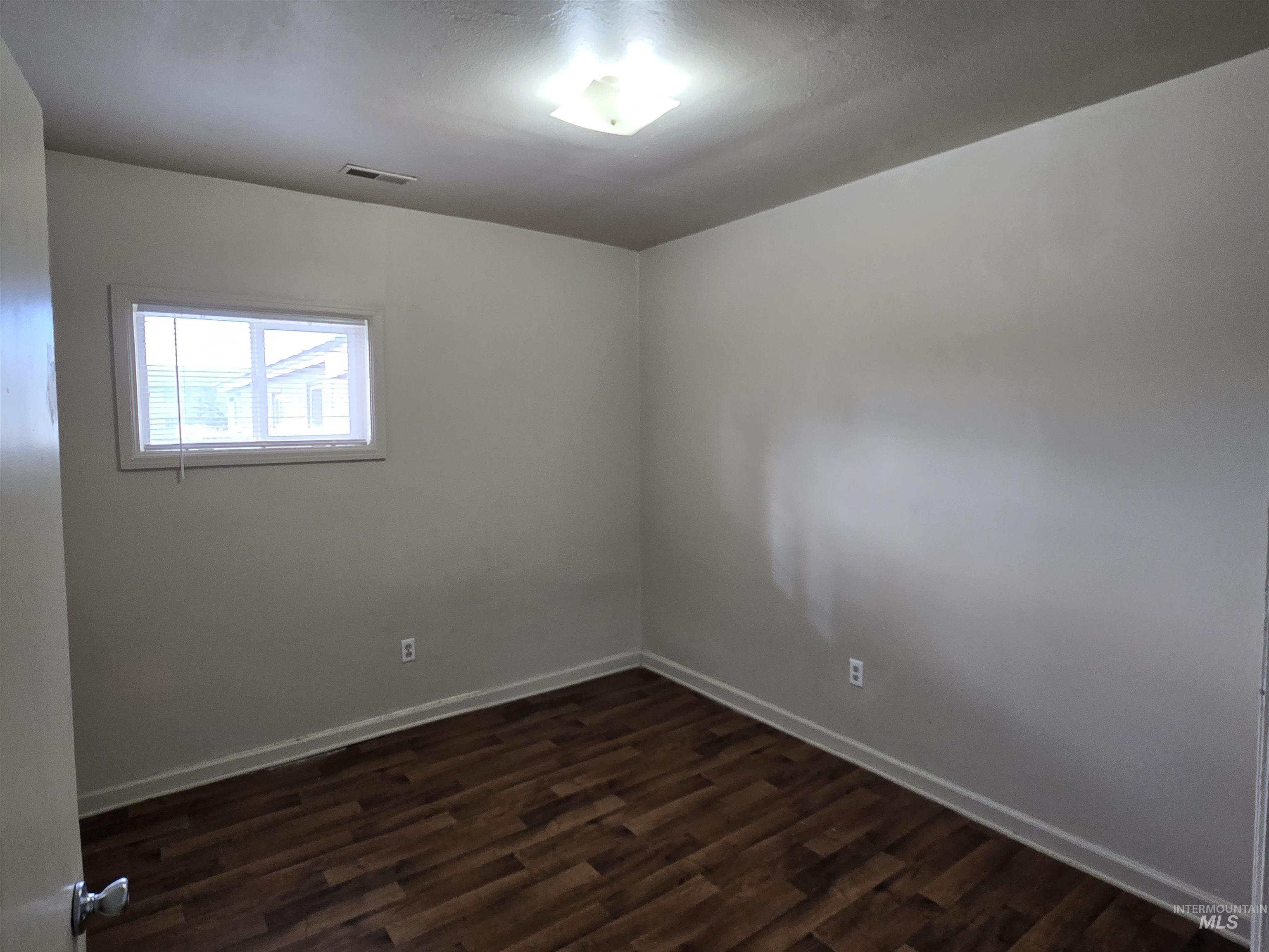 Empty room with dark wood finished floors and baseboards