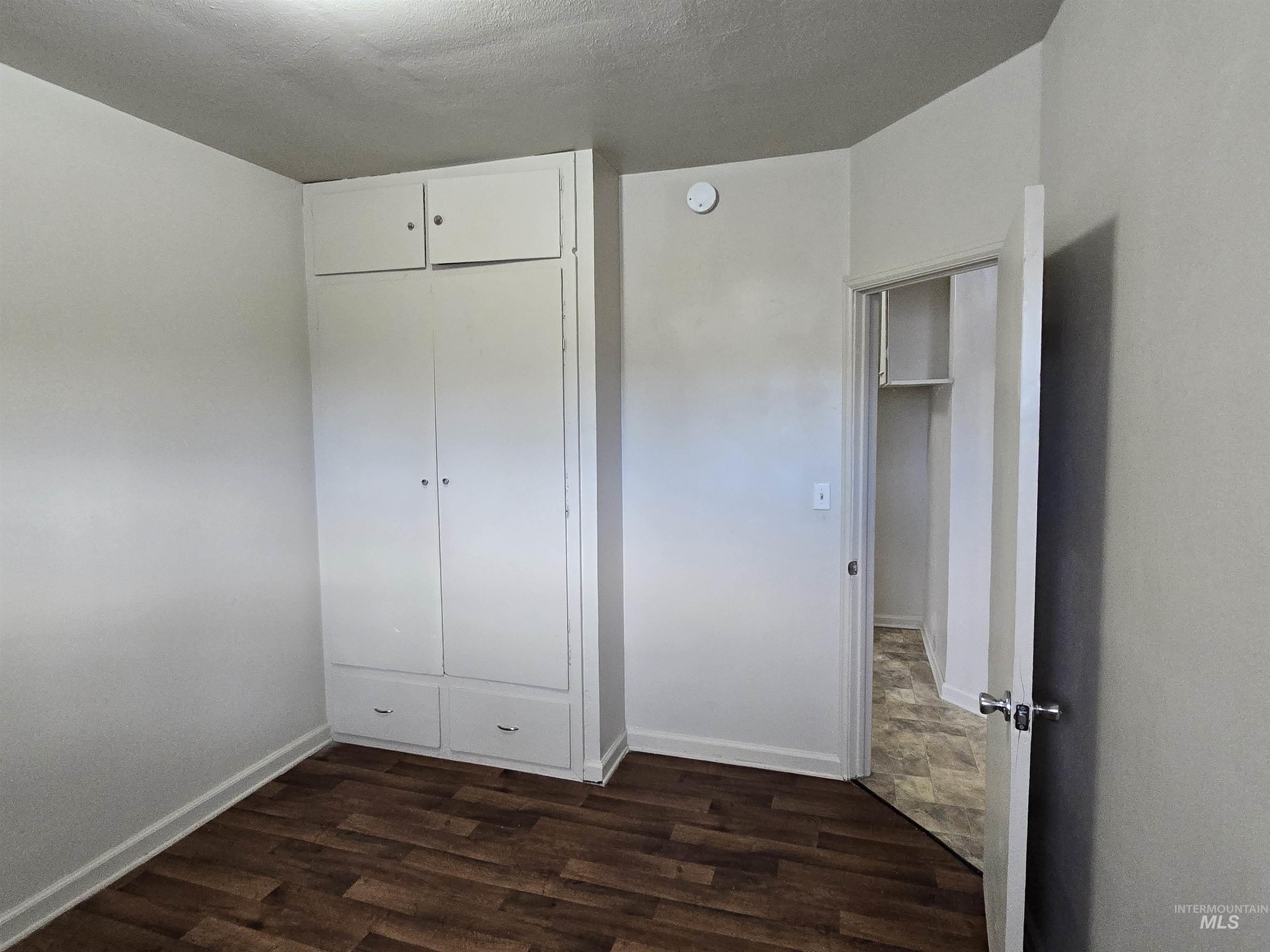 Unfurnished bedroom featuring a closet, dark wood-style floors, and a textured ceiling