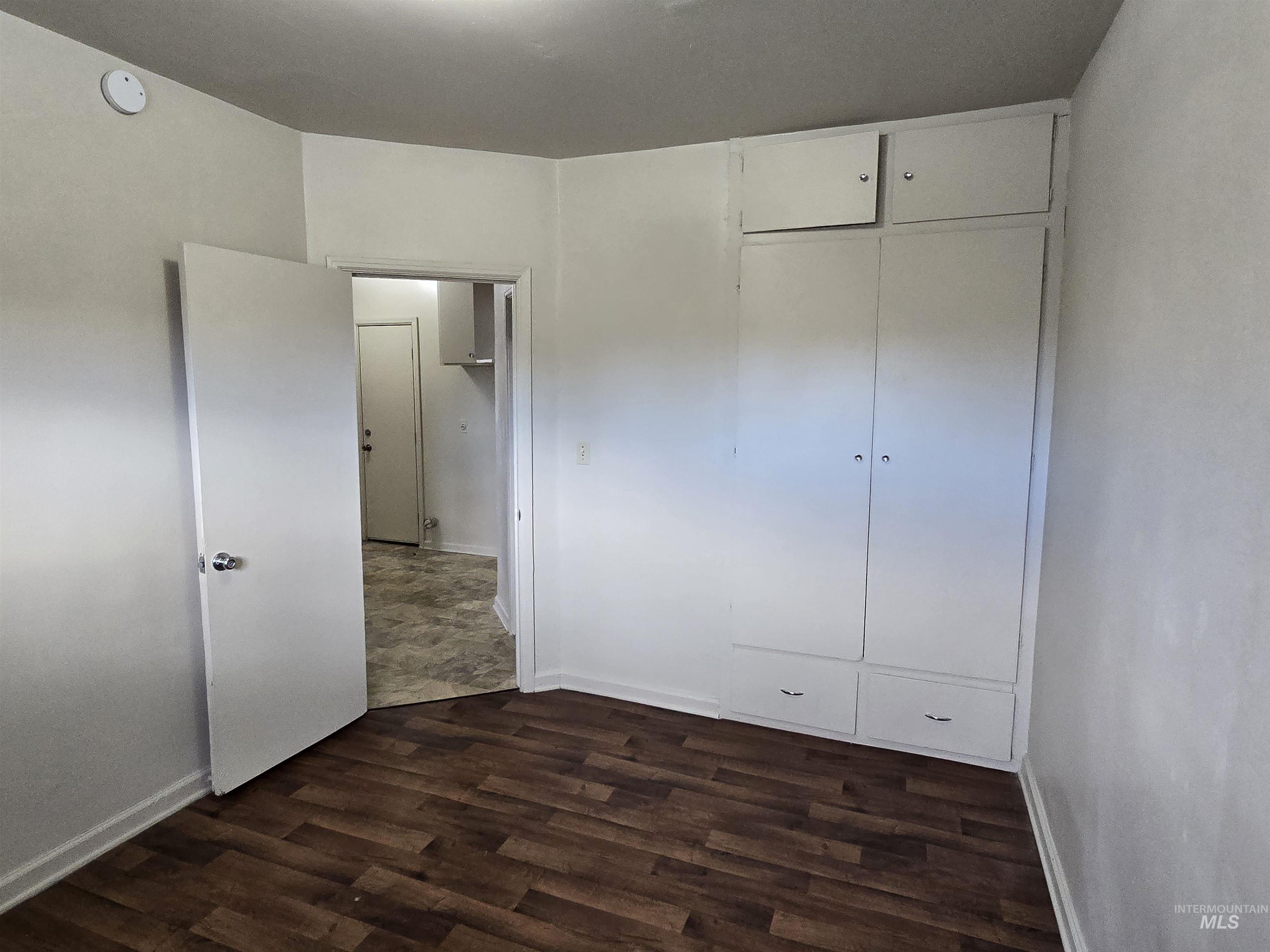 Unfurnished bedroom featuring a closet and dark wood-style floors