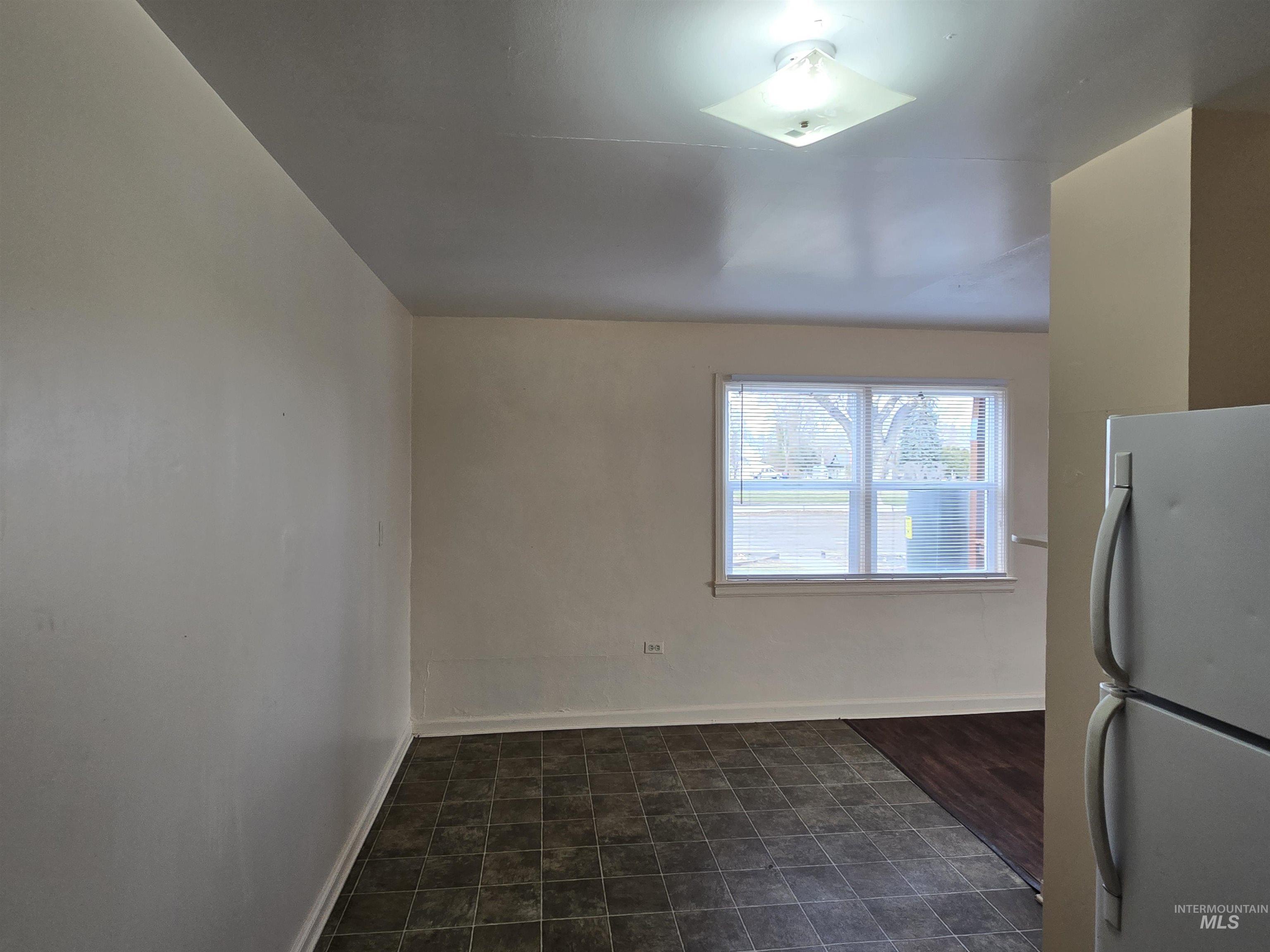 Unfurnished dining area with baseboards and dark tile patterned floors