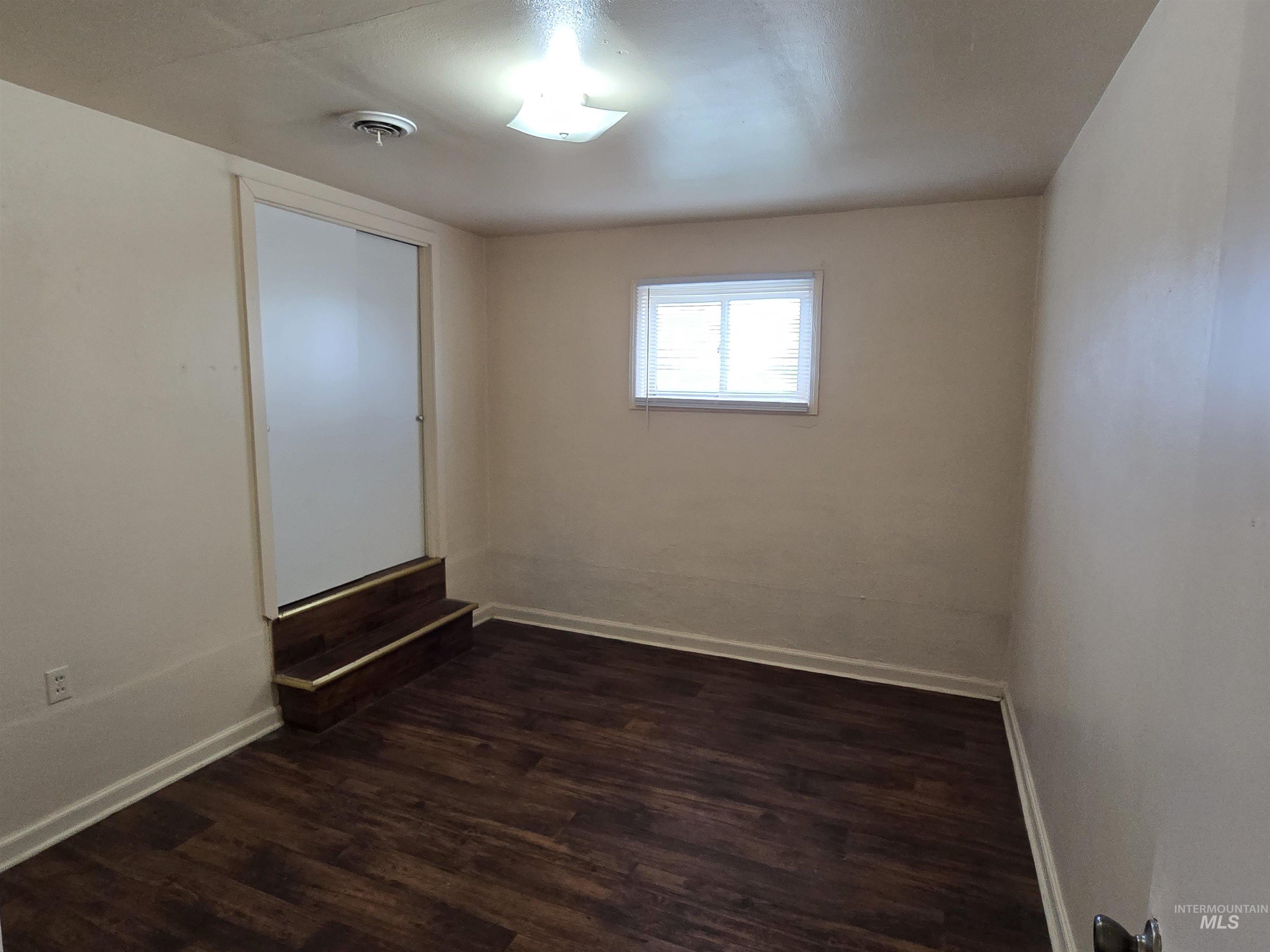 Unfurnished room with dark wood-style floors and baseboards