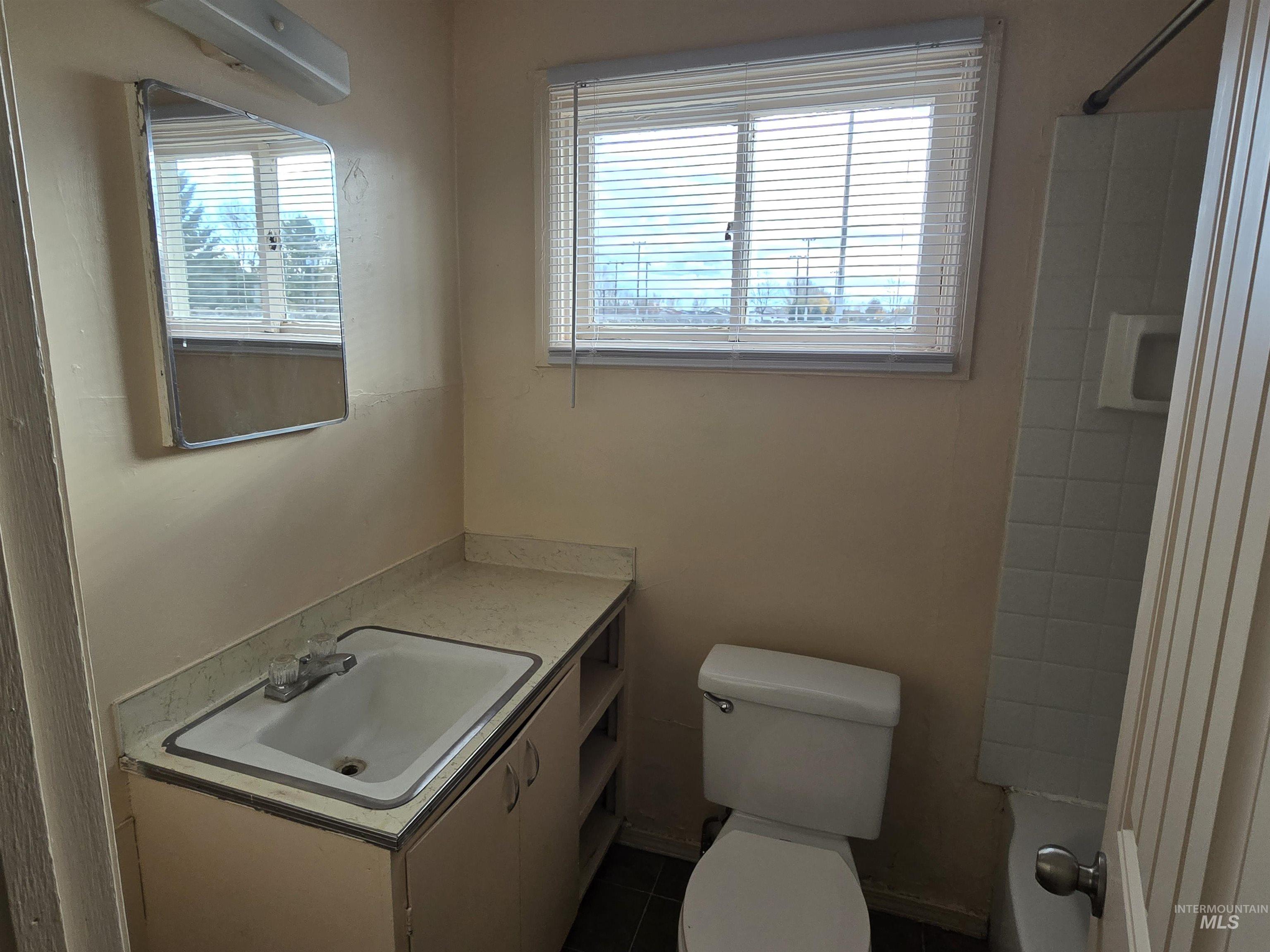 Bathroom with vanity, shower / bath combination, and dark tile patterned flooring