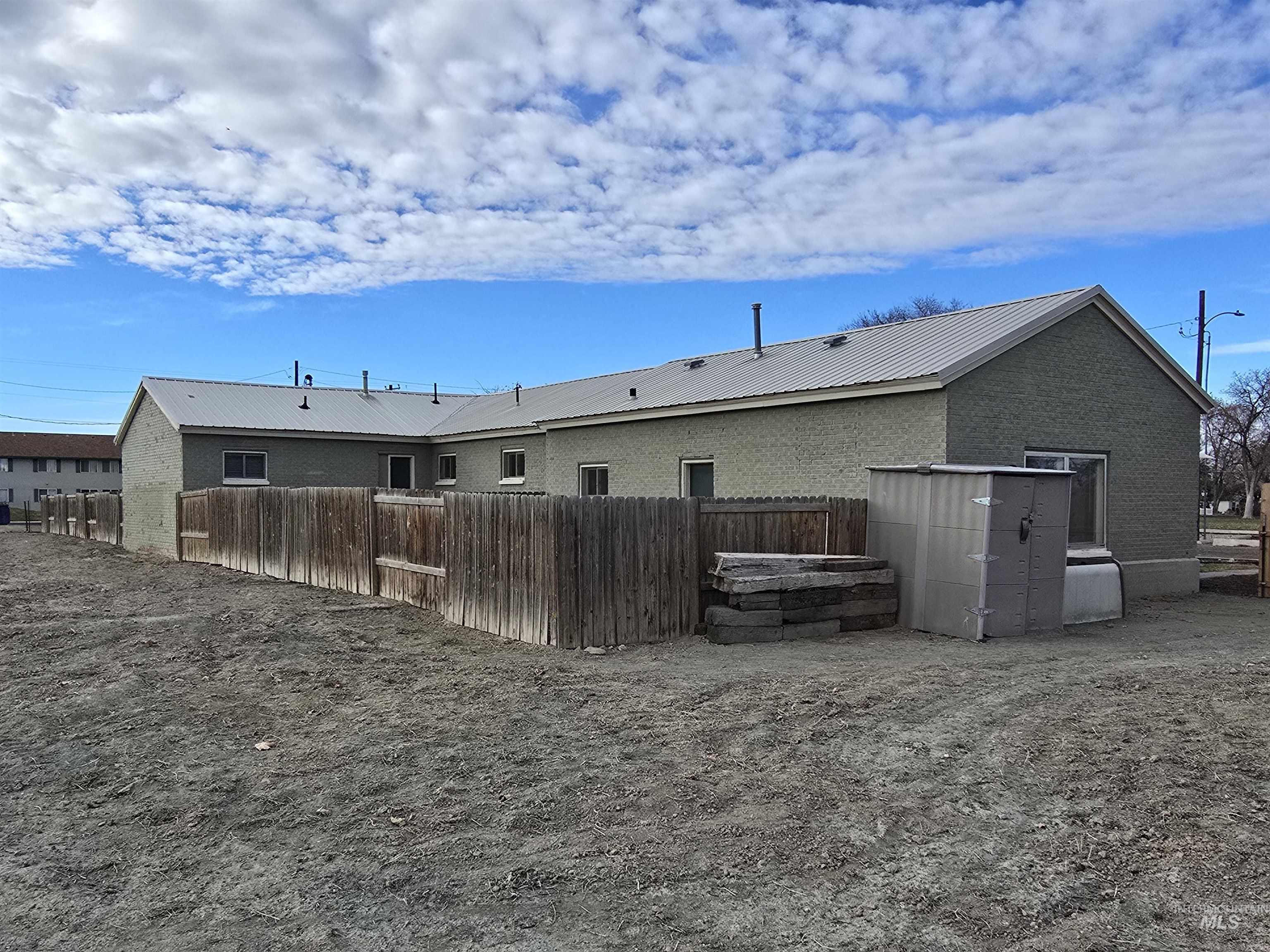 Rear view of property with a metal roof and brick siding