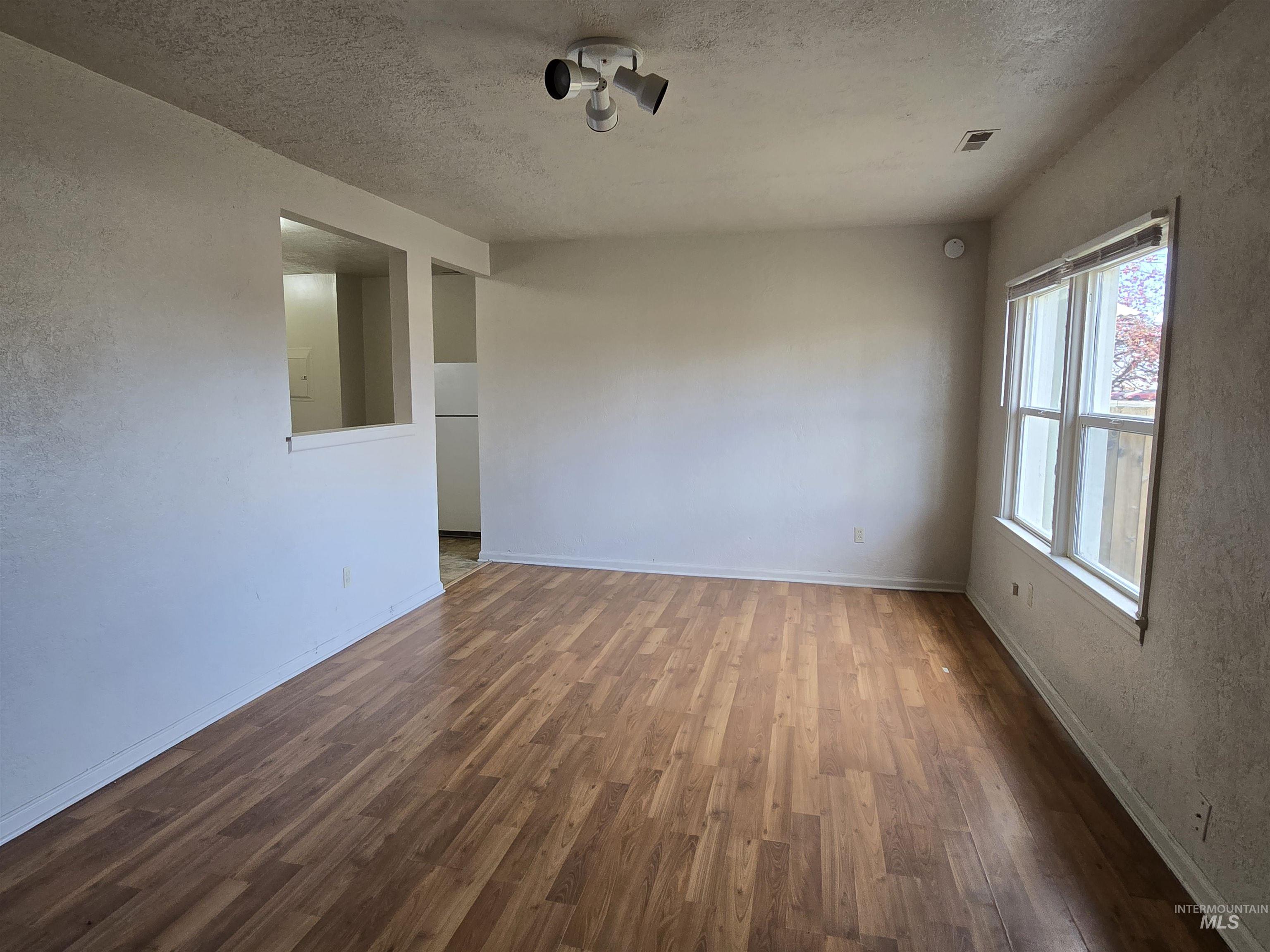 Spare room with dark wood-style flooring, a textured ceiling, and a textured wall