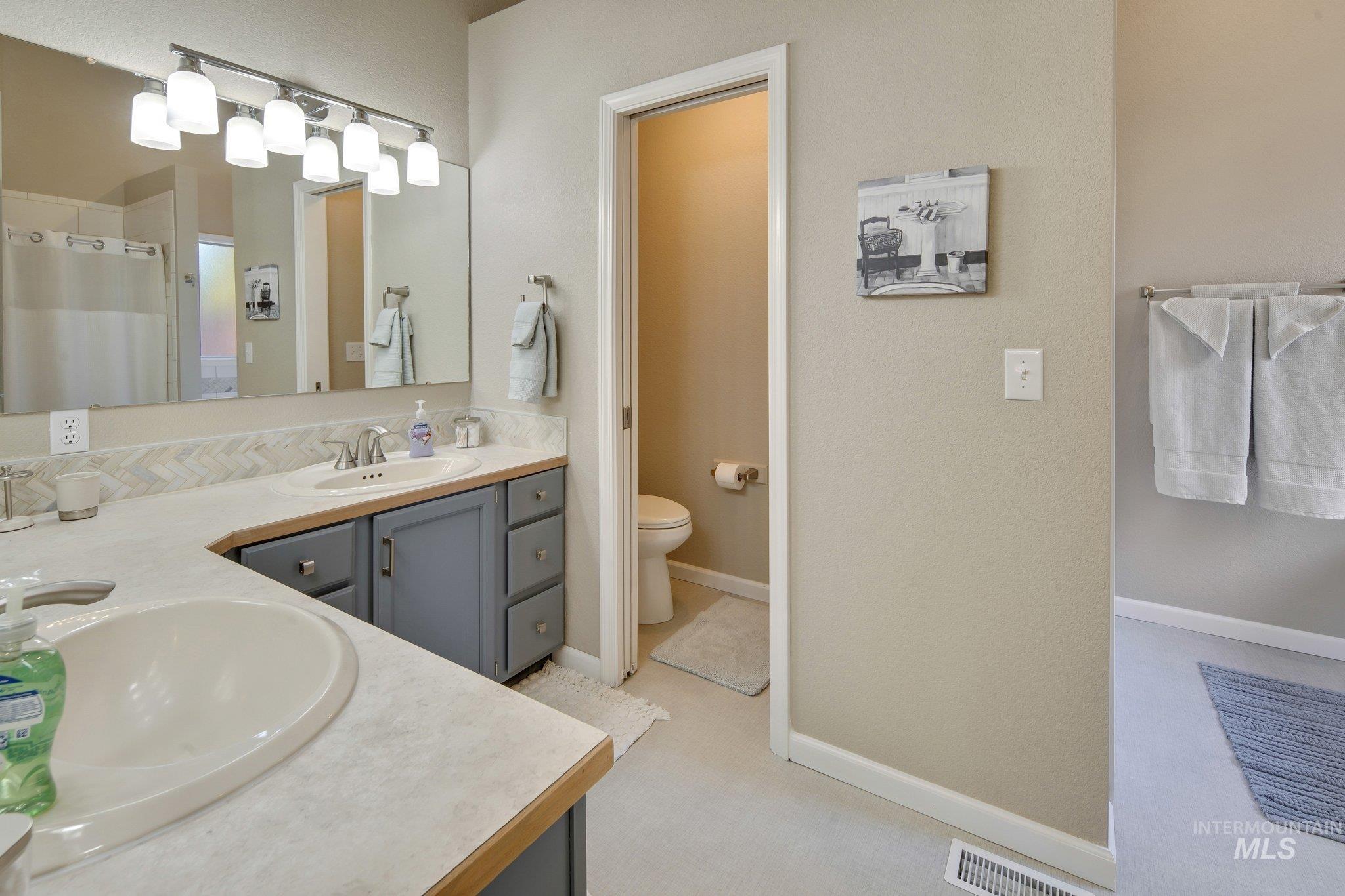 Full bath featuring a shower with shower curtain and double vanity