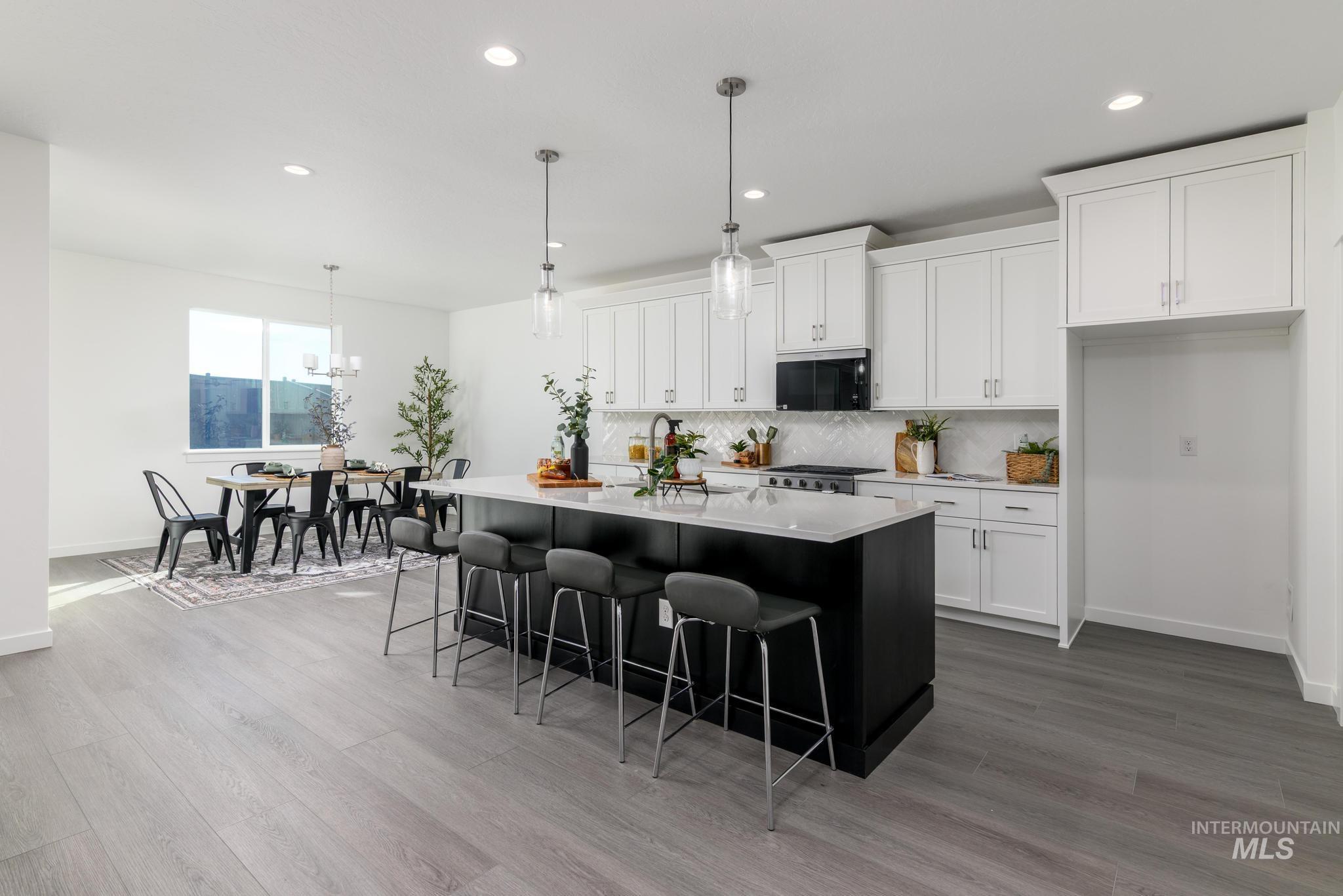 Kitchen with dark cabinetry, tasteful backsplash, white cabinetry, hanging light fixtures, and recessed lighting
