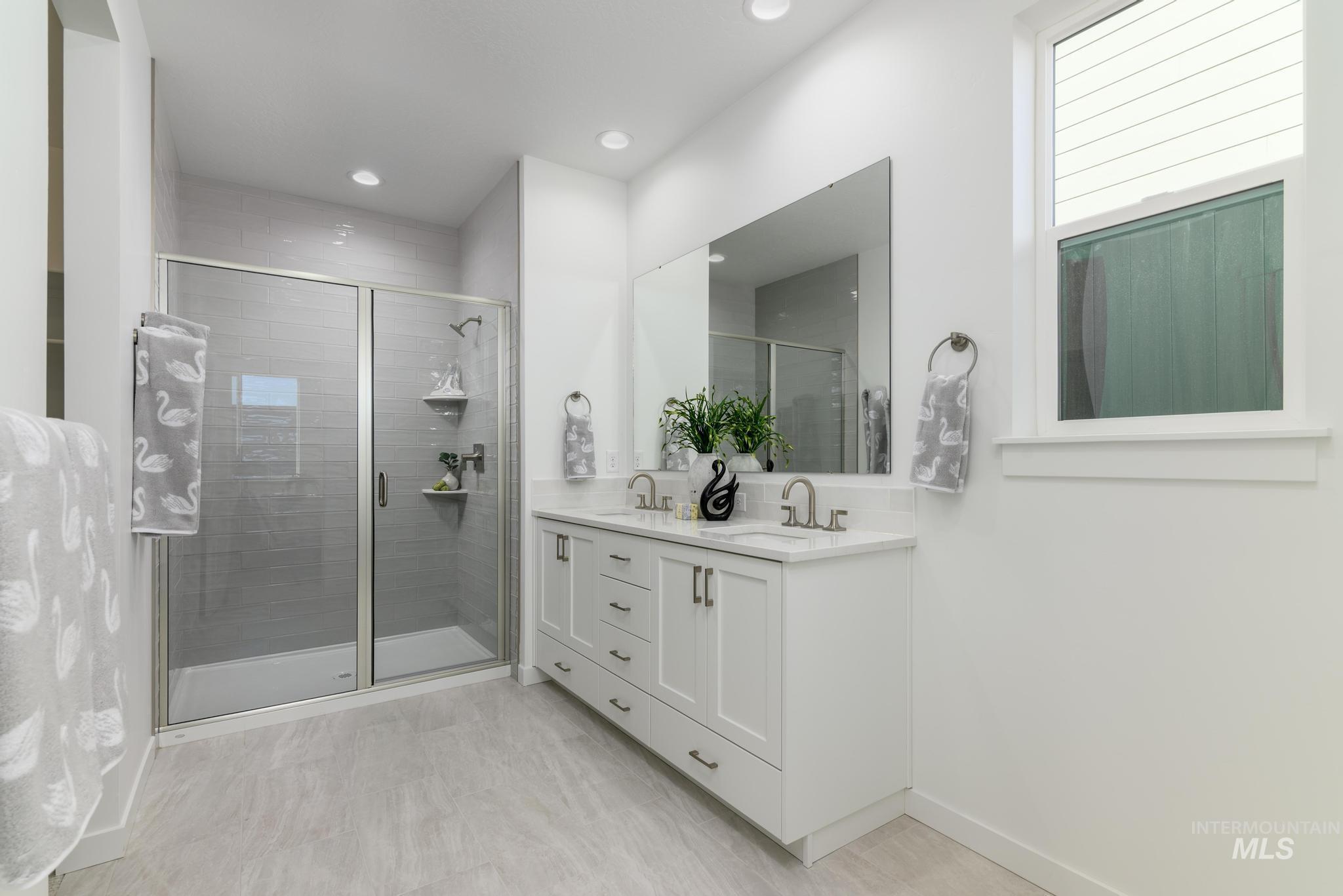 Bathroom with double vanity, a shower stall, and recessed lighting