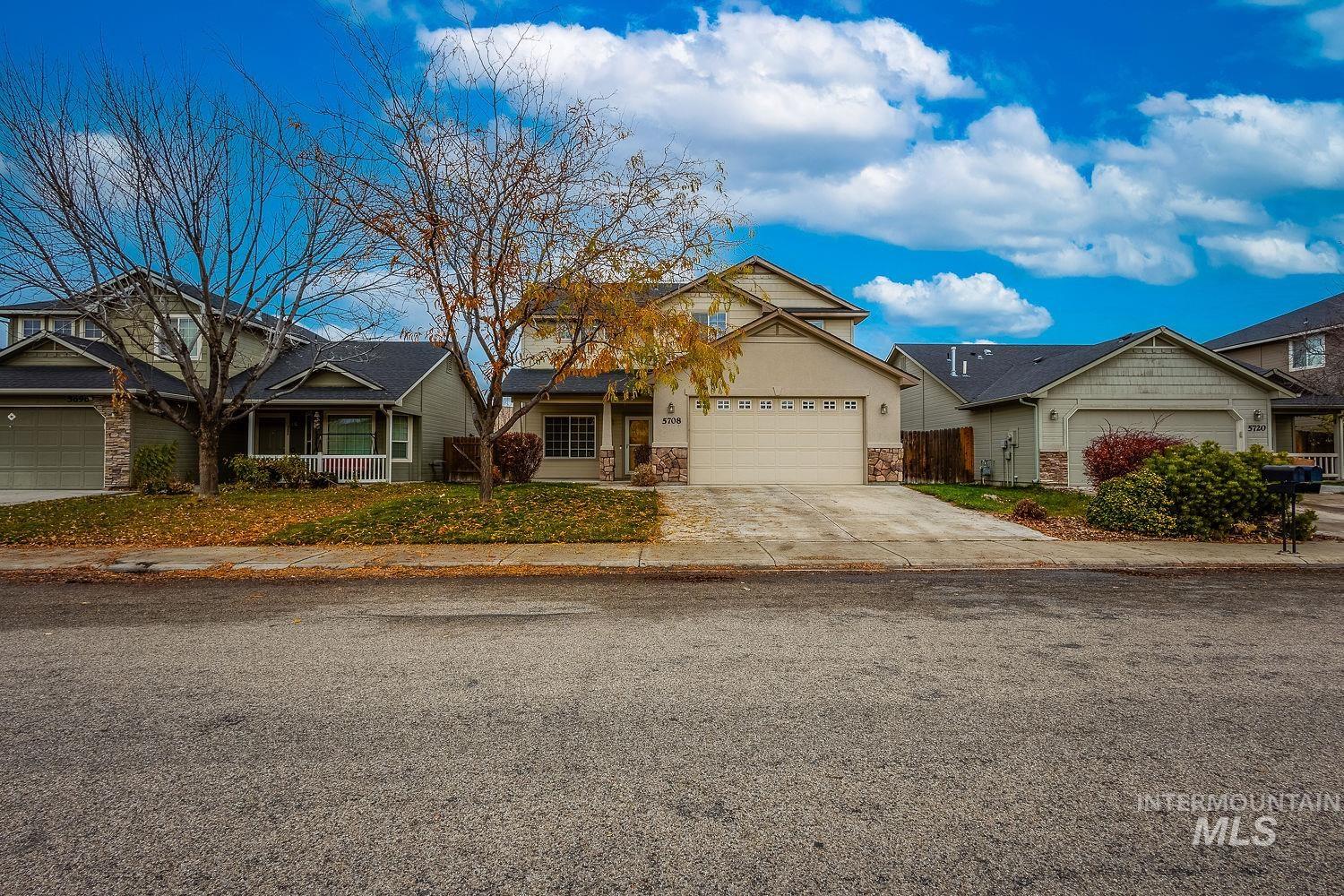 View of front of home featuring concrete driveway, stone siding, a residential view, and an attached garage