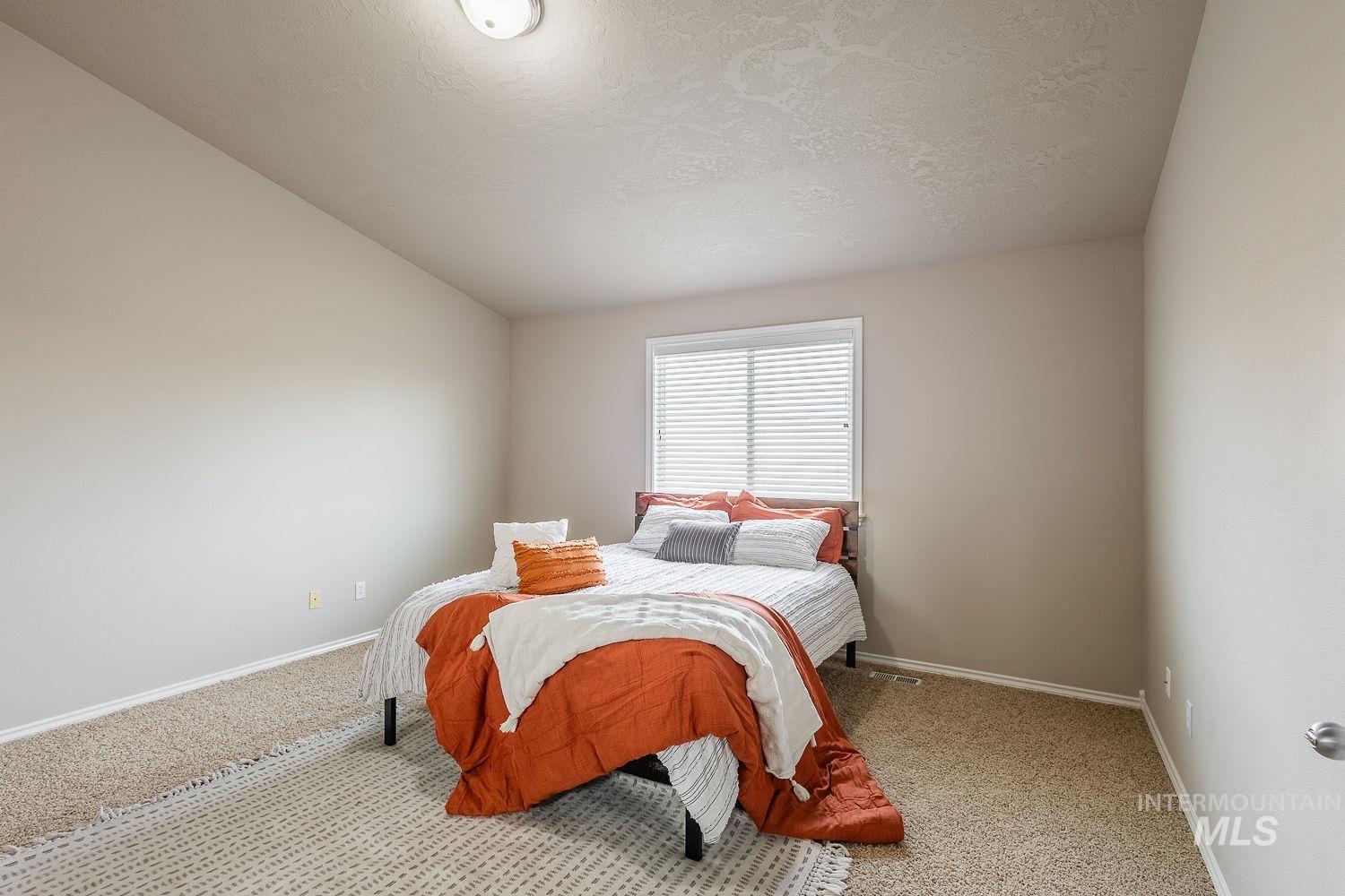 Bedroom with carpet flooring, a textured ceiling, and vaulted ceiling