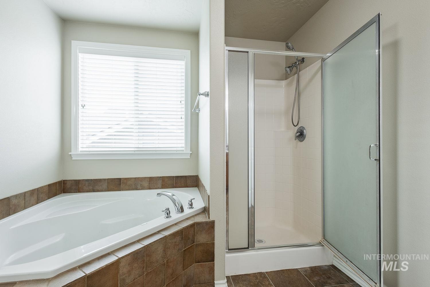 Full bath with a shower stall, a garden tub, and dark tile patterned flooring