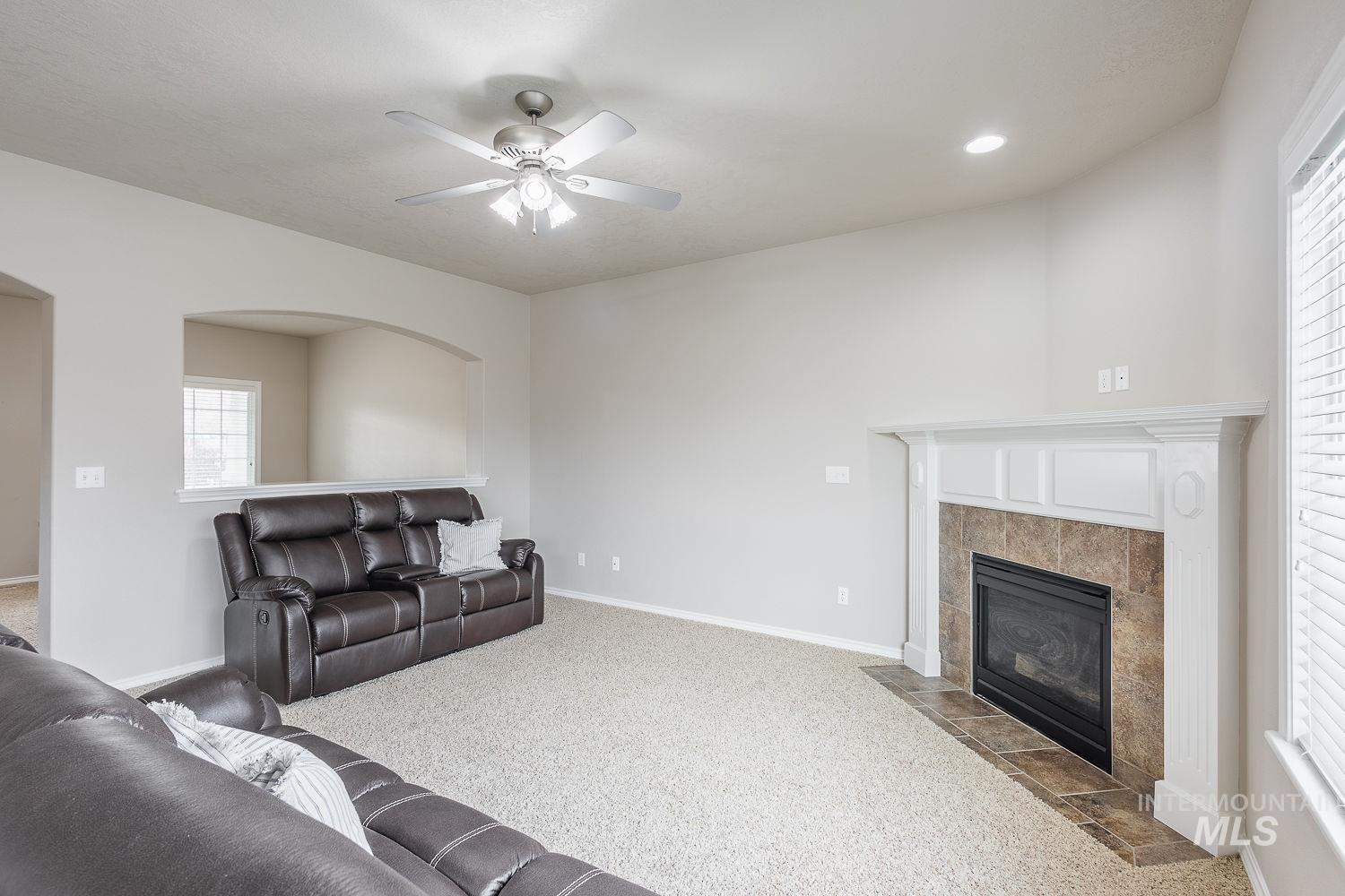 Carpeted living room with a tile fireplace, a ceiling fan, and recessed lighting