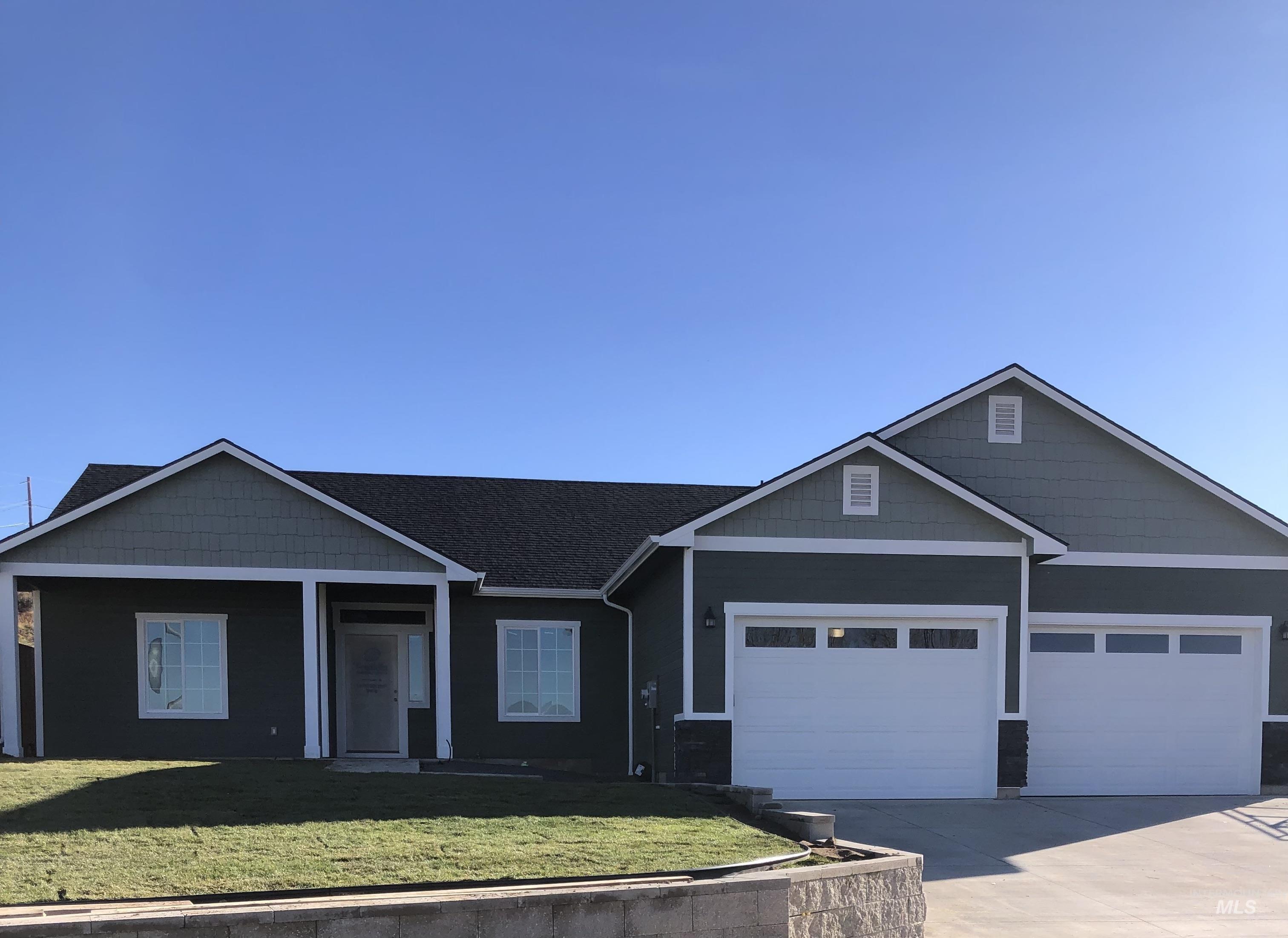 View of front facade featuring concrete driveway, a front yard, an attached garage, and covered porch