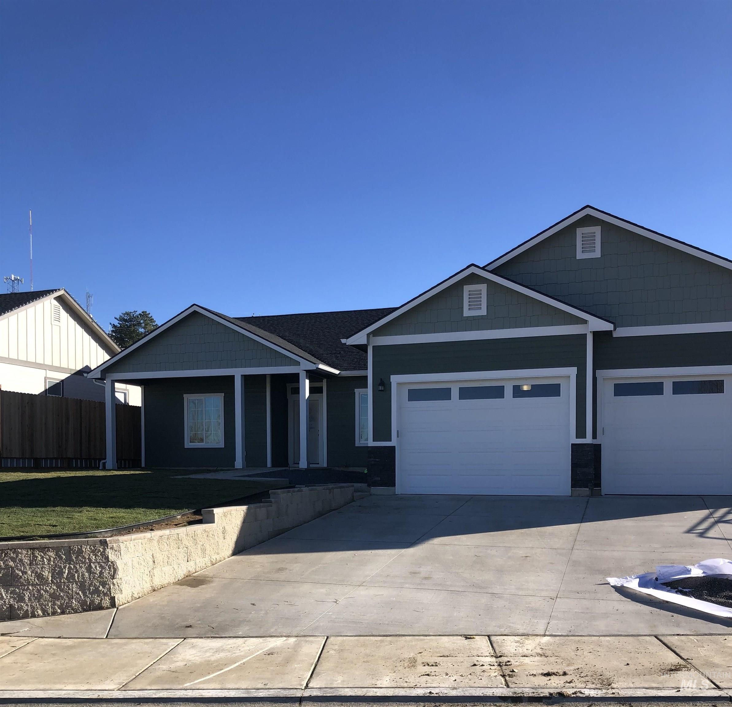 View of front facade featuring driveway, a porch, a garage, and a front yard
