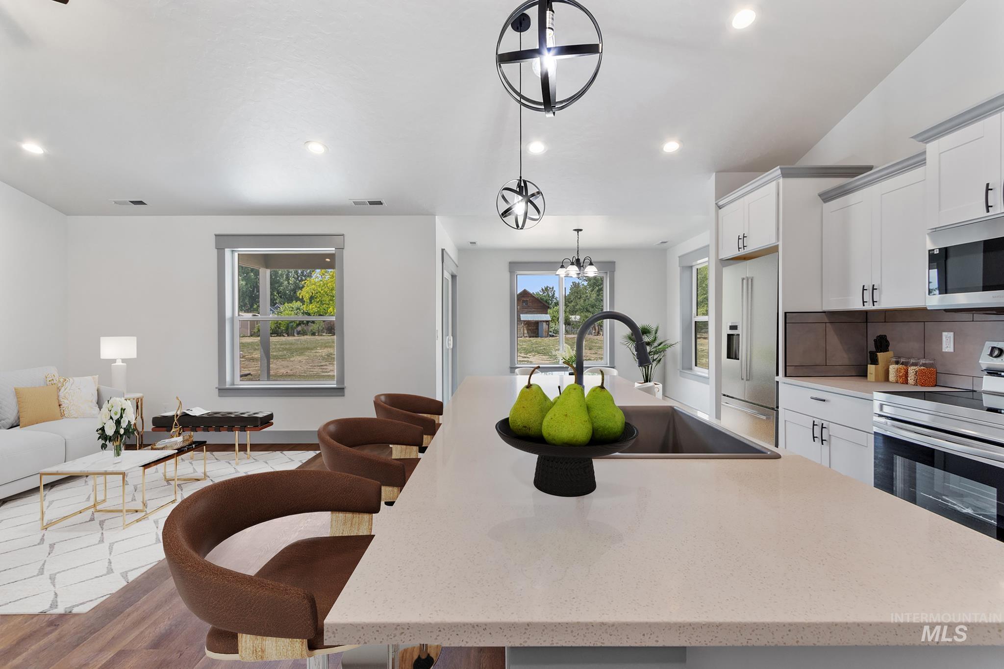 Kitchen featuring an island with sink, stainless steel appliances, white cabinets, light stone counters, and recessed lighting