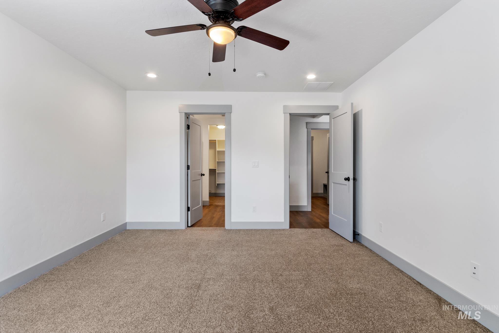Unfurnished bedroom with light carpet, recessed lighting, a ceiling fan, and a walk in closet