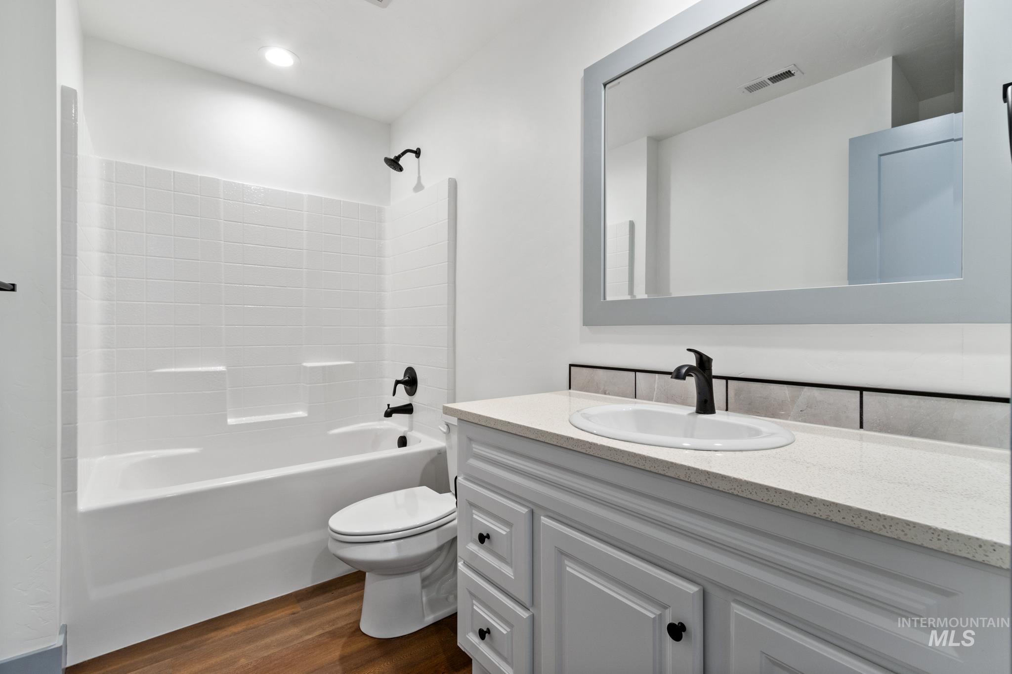 Full bathroom with dark wood-style floors, vanity, and shower / bathtub combination