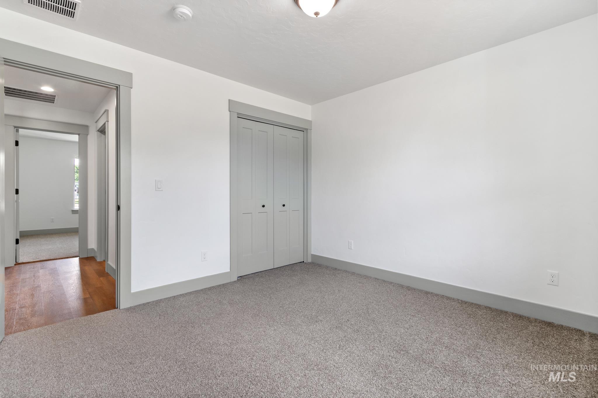 Unfurnished bedroom with light carpet and a closet