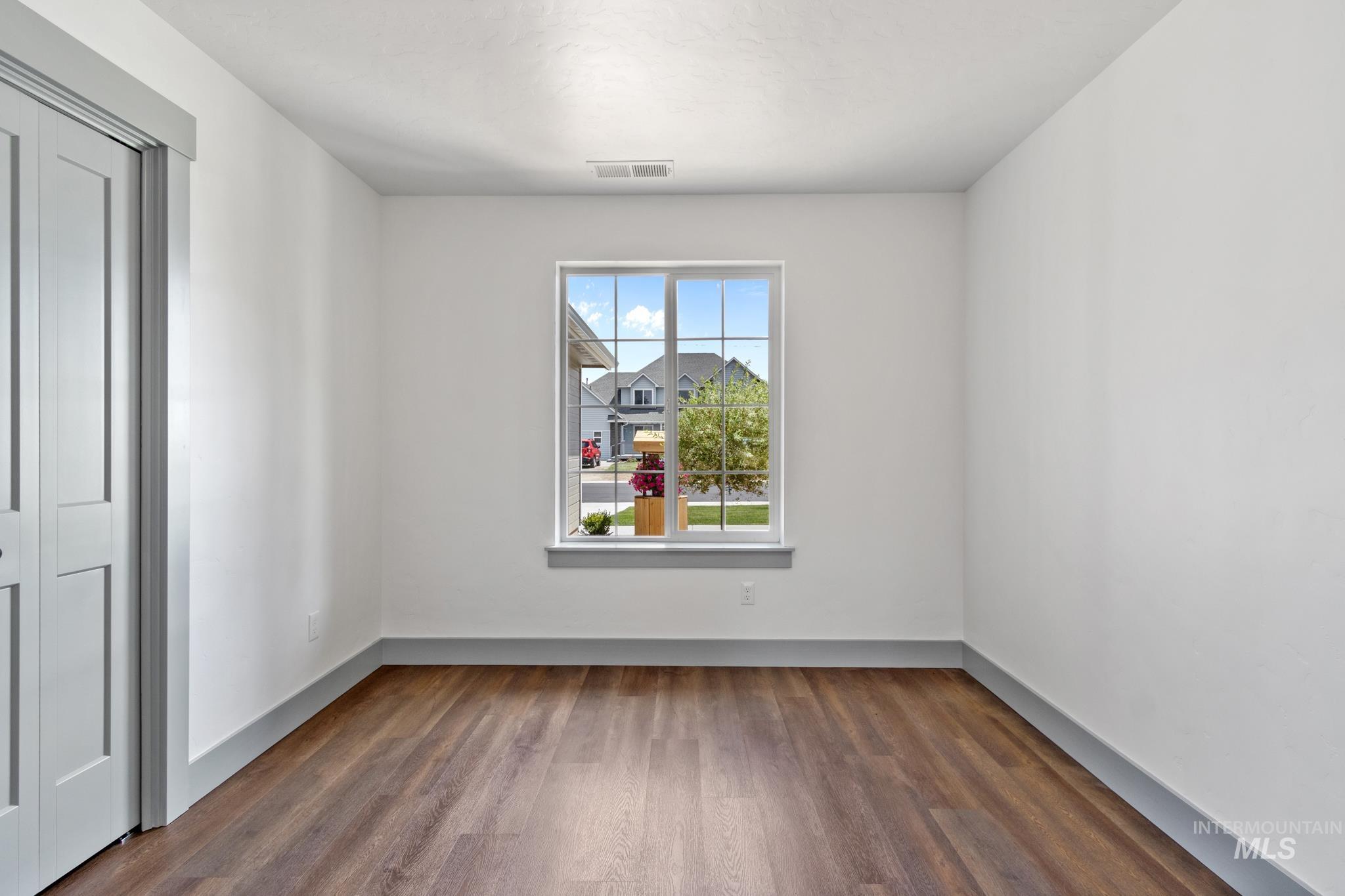 Spare room featuring dark wood-type flooring and baseboards
