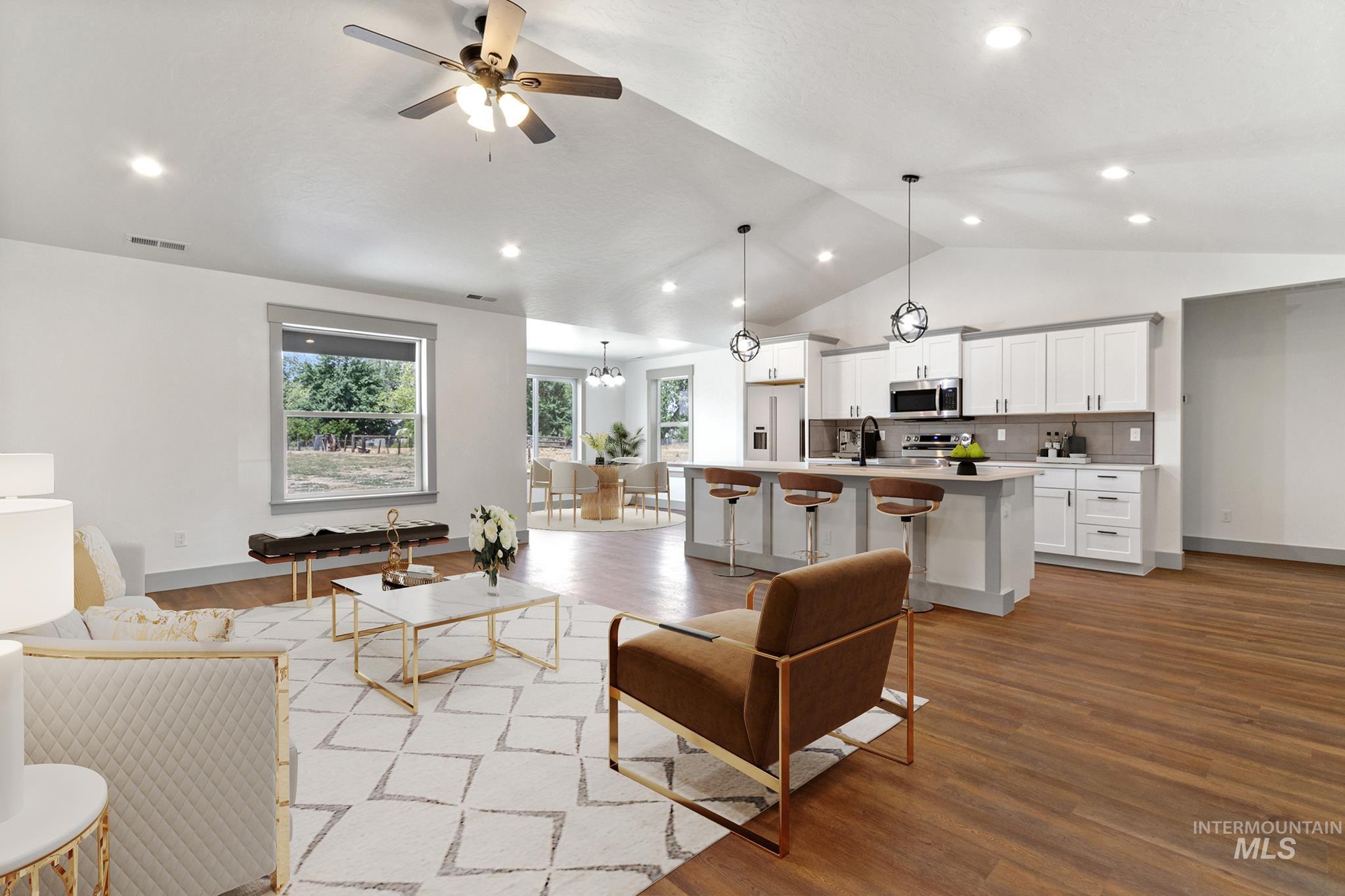 Living room featuring lofted ceiling, light wood finished floors, a ceiling fan, recessed lighting, and a chandelier