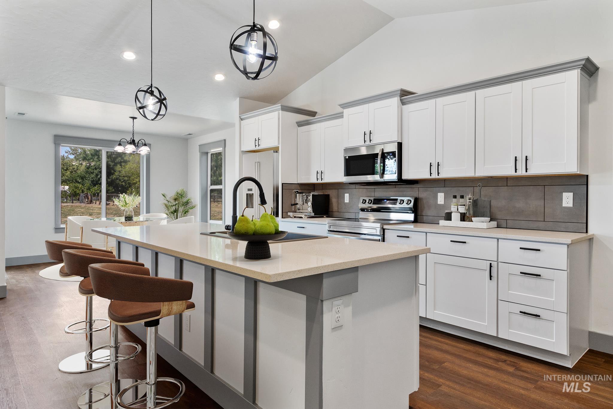 Kitchen featuring white cabinets, stainless steel appliances, a kitchen breakfast bar, a kitchen island with sink, and recessed lighting
