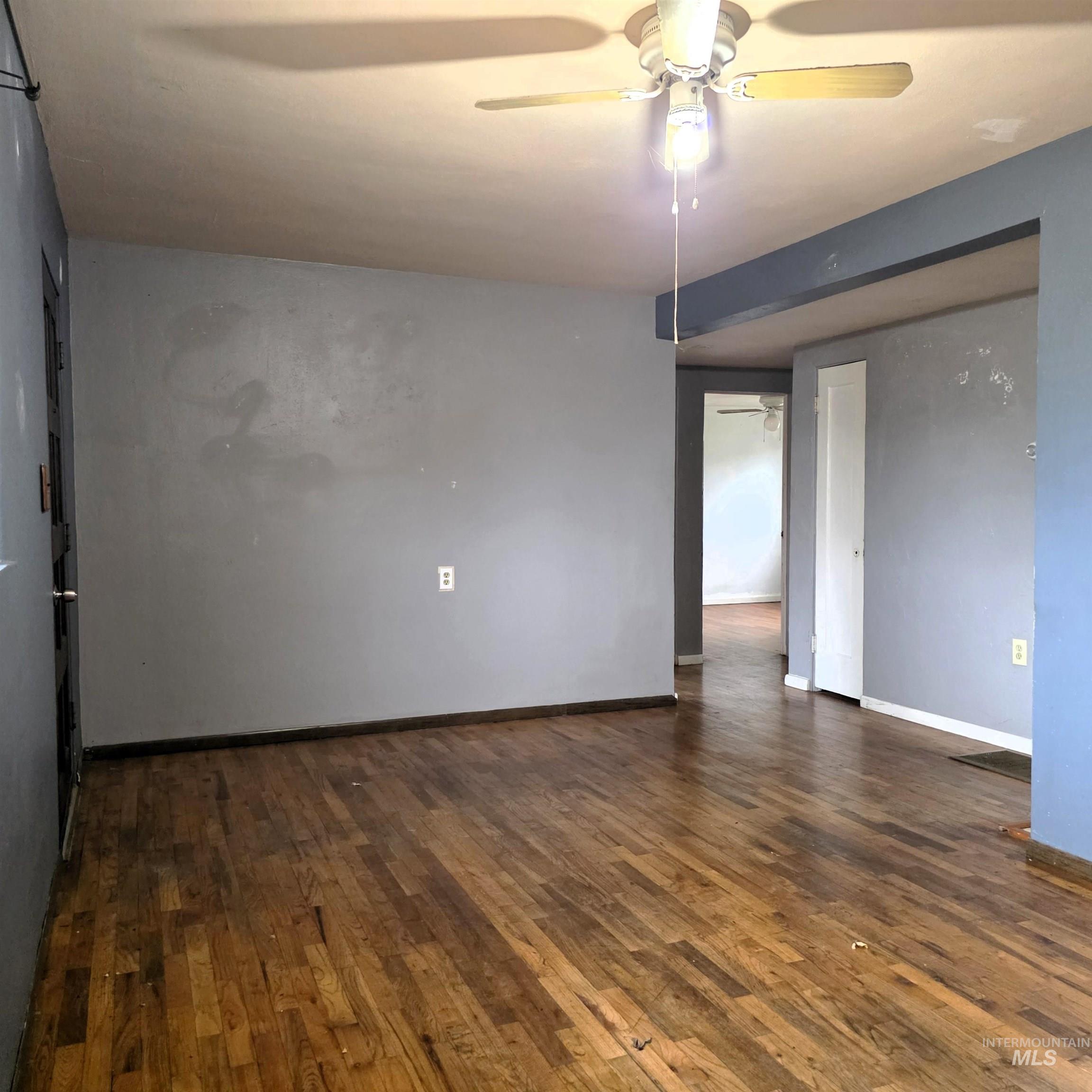Unfurnished room featuring dark wood-style floors and a ceiling fan
