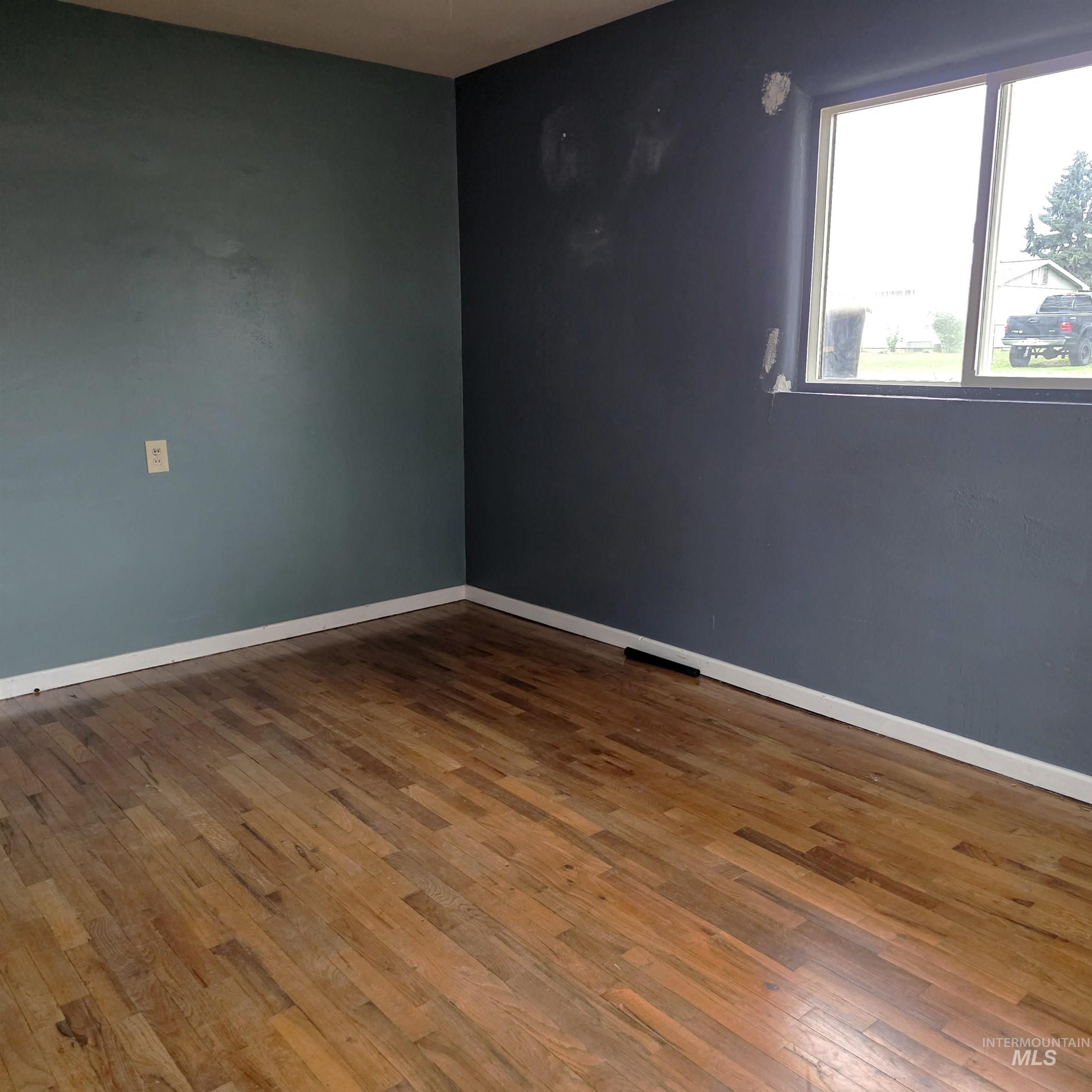 Empty room featuring hardwood / wood-style flooring and baseboards