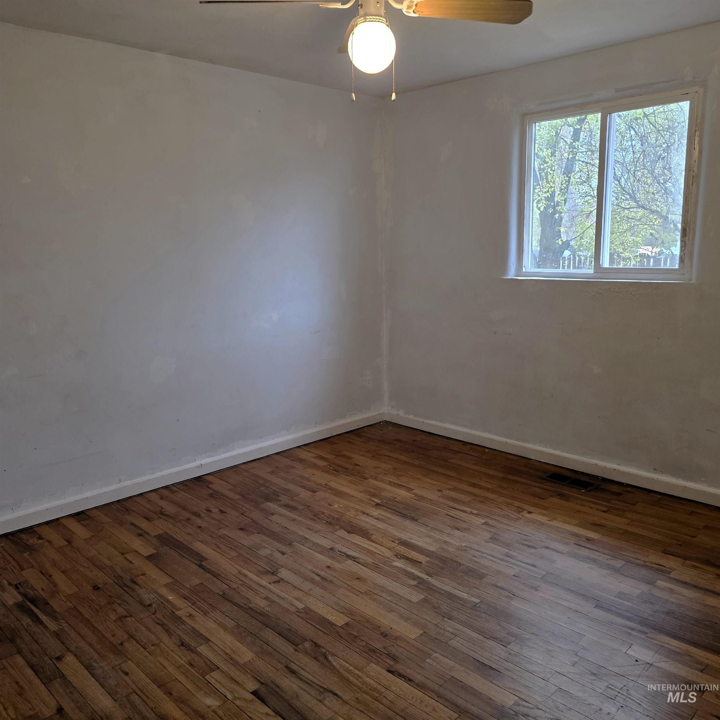 Unfurnished room featuring dark wood finished floors and ceiling fan