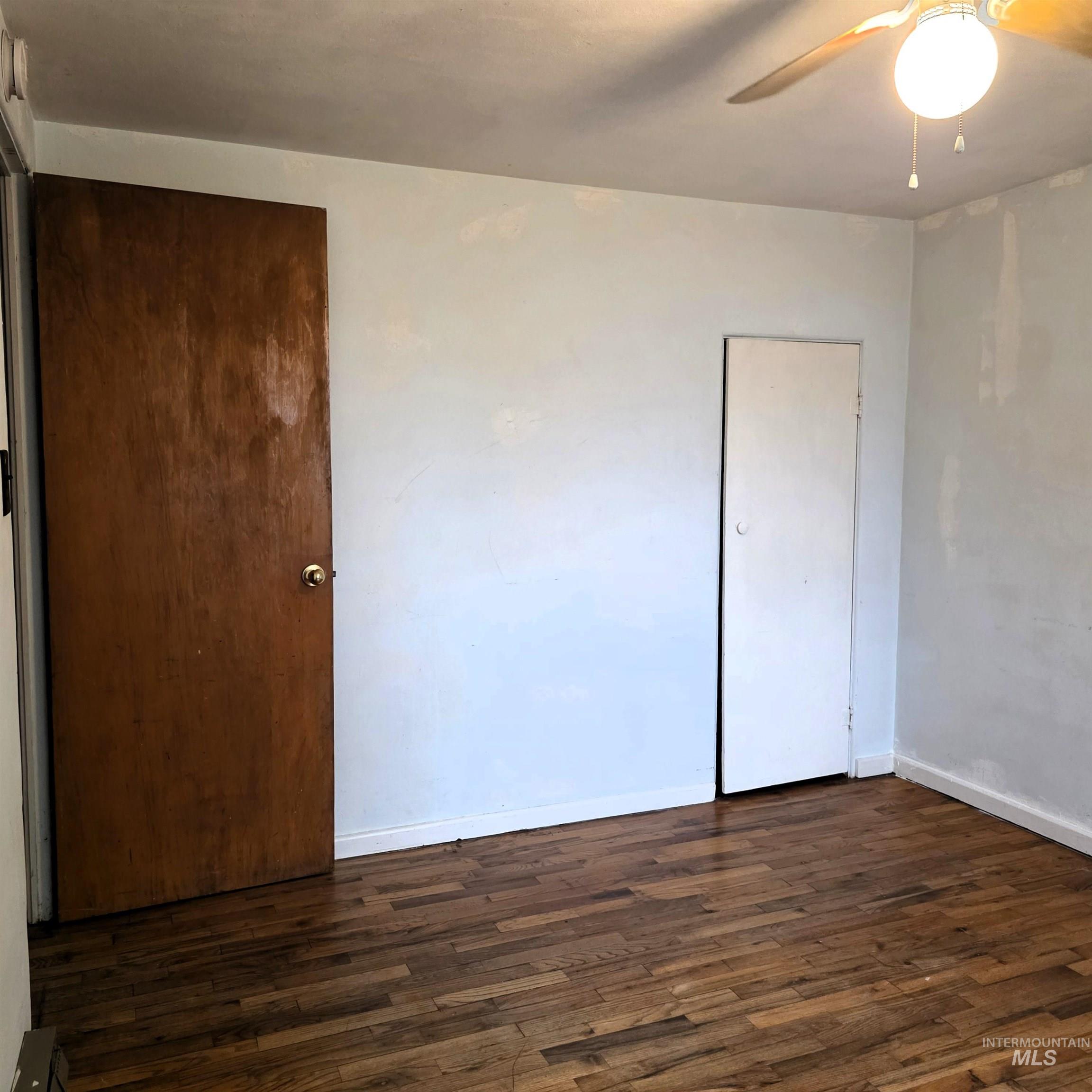 Unfurnished bedroom with dark wood-style floors and a ceiling fan