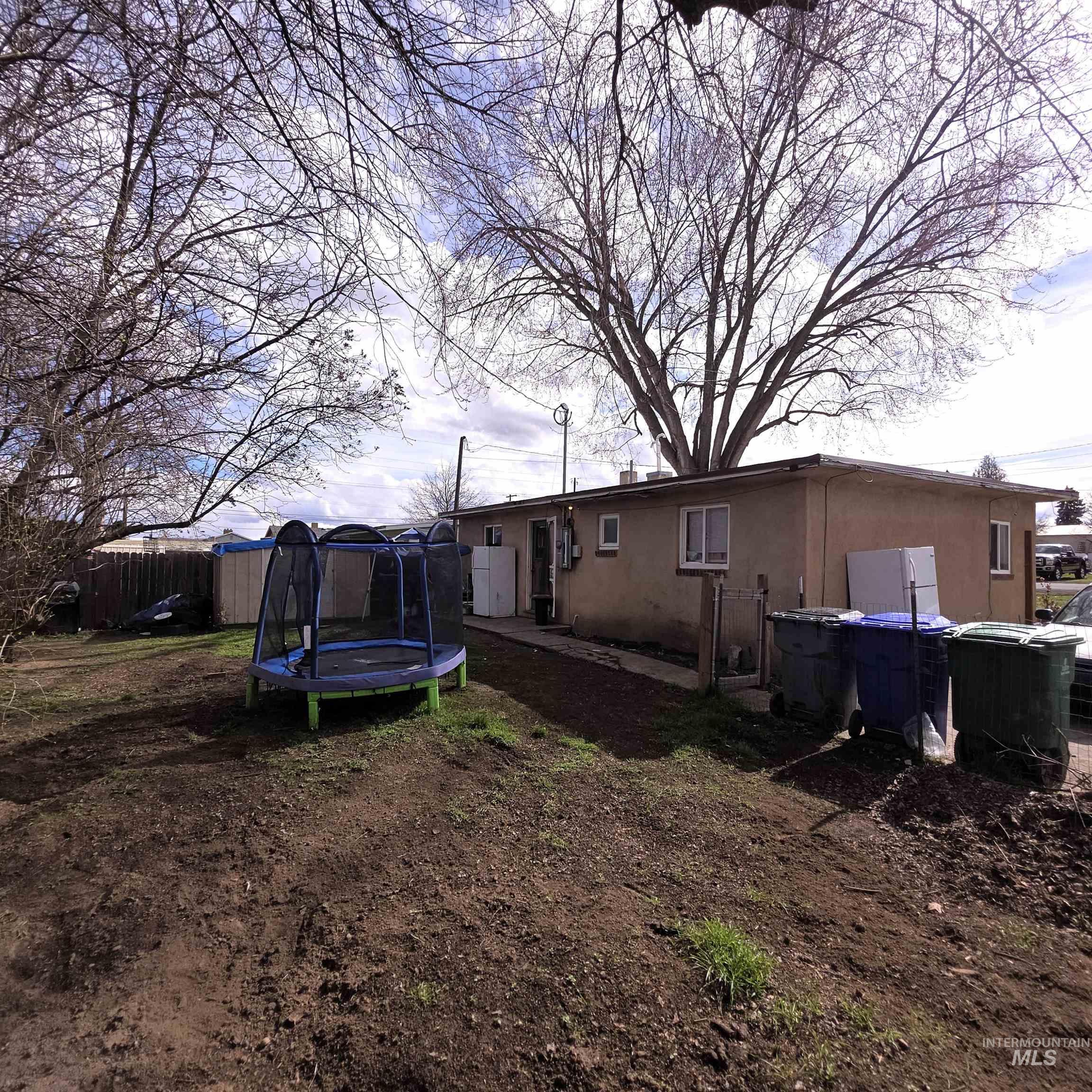 Back of house featuring a trampoline and stucco siding
