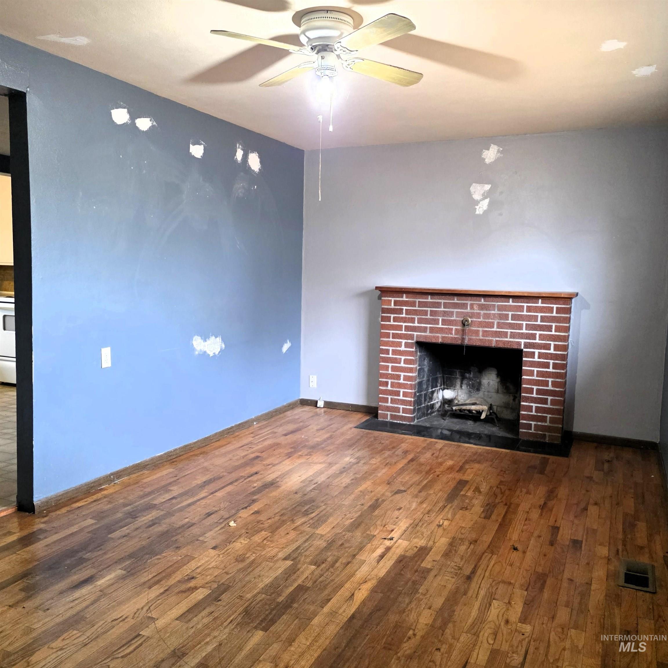 Unfurnished living room with dark wood-style flooring, a fireplace, and a ceiling fan