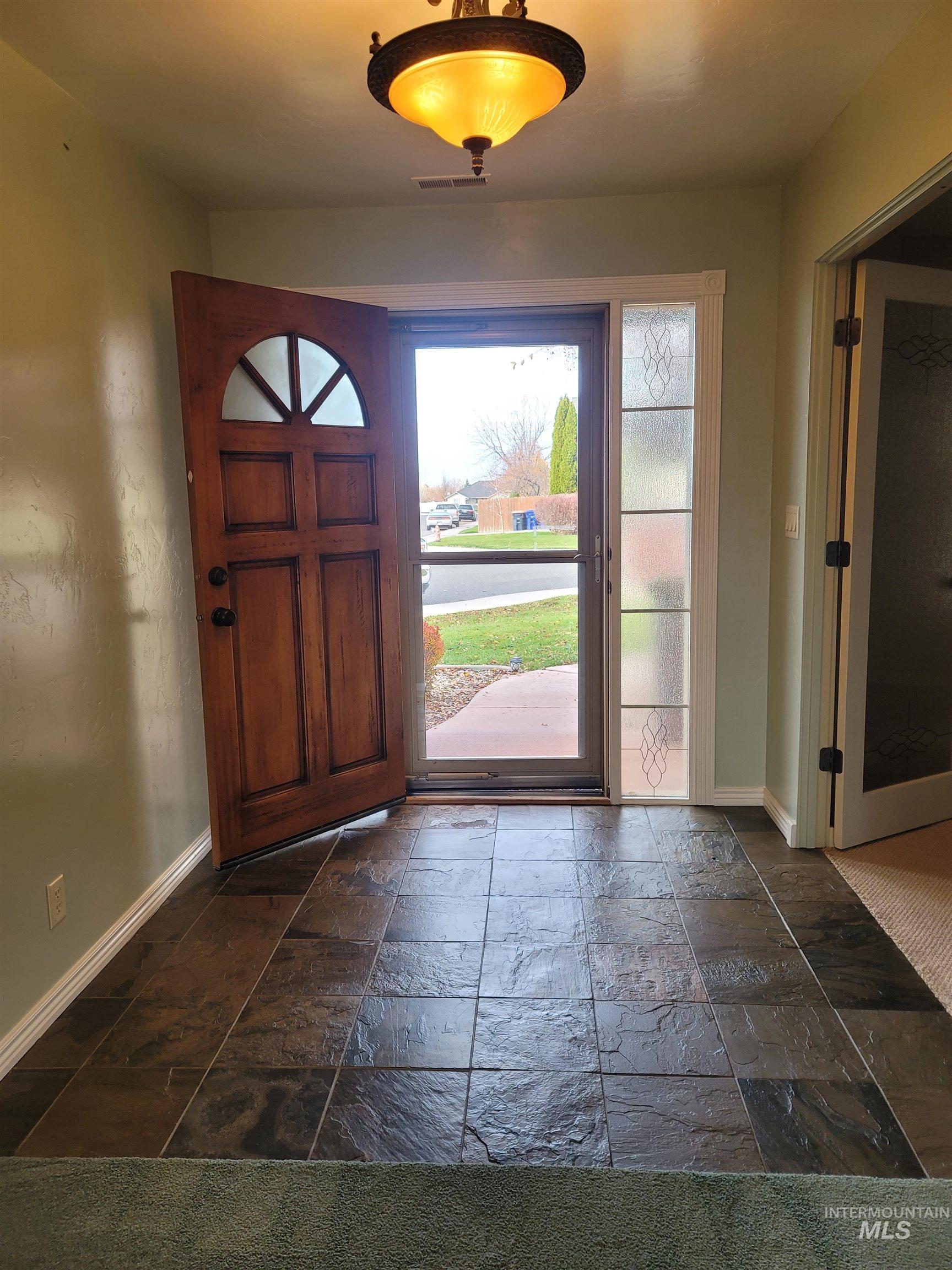 Foyer entrance with baseboards and stone tile floors