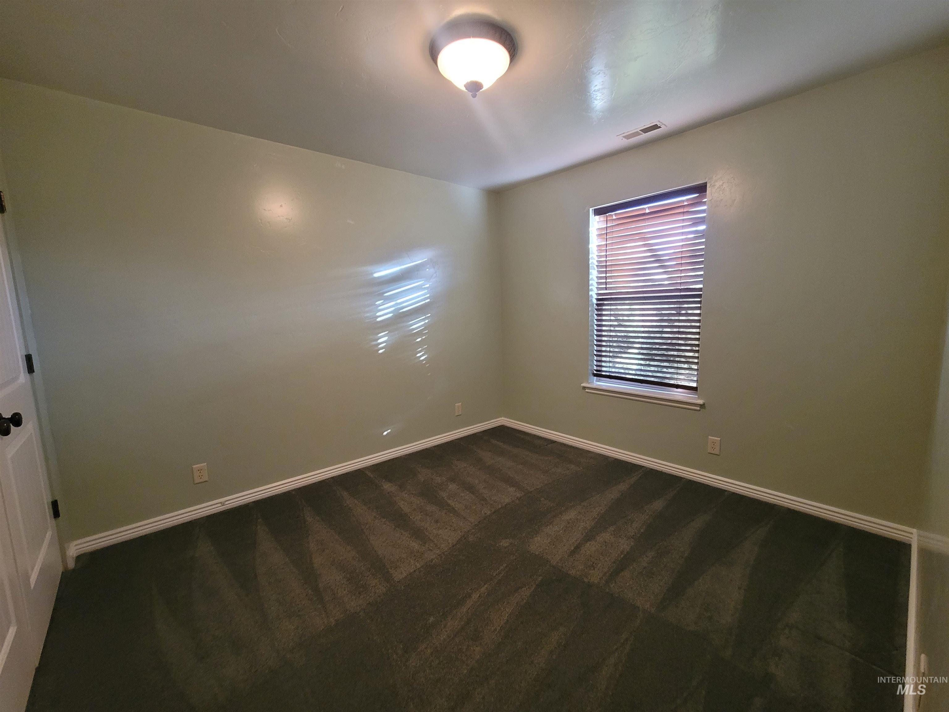 Empty room with dark colored carpet and baseboards