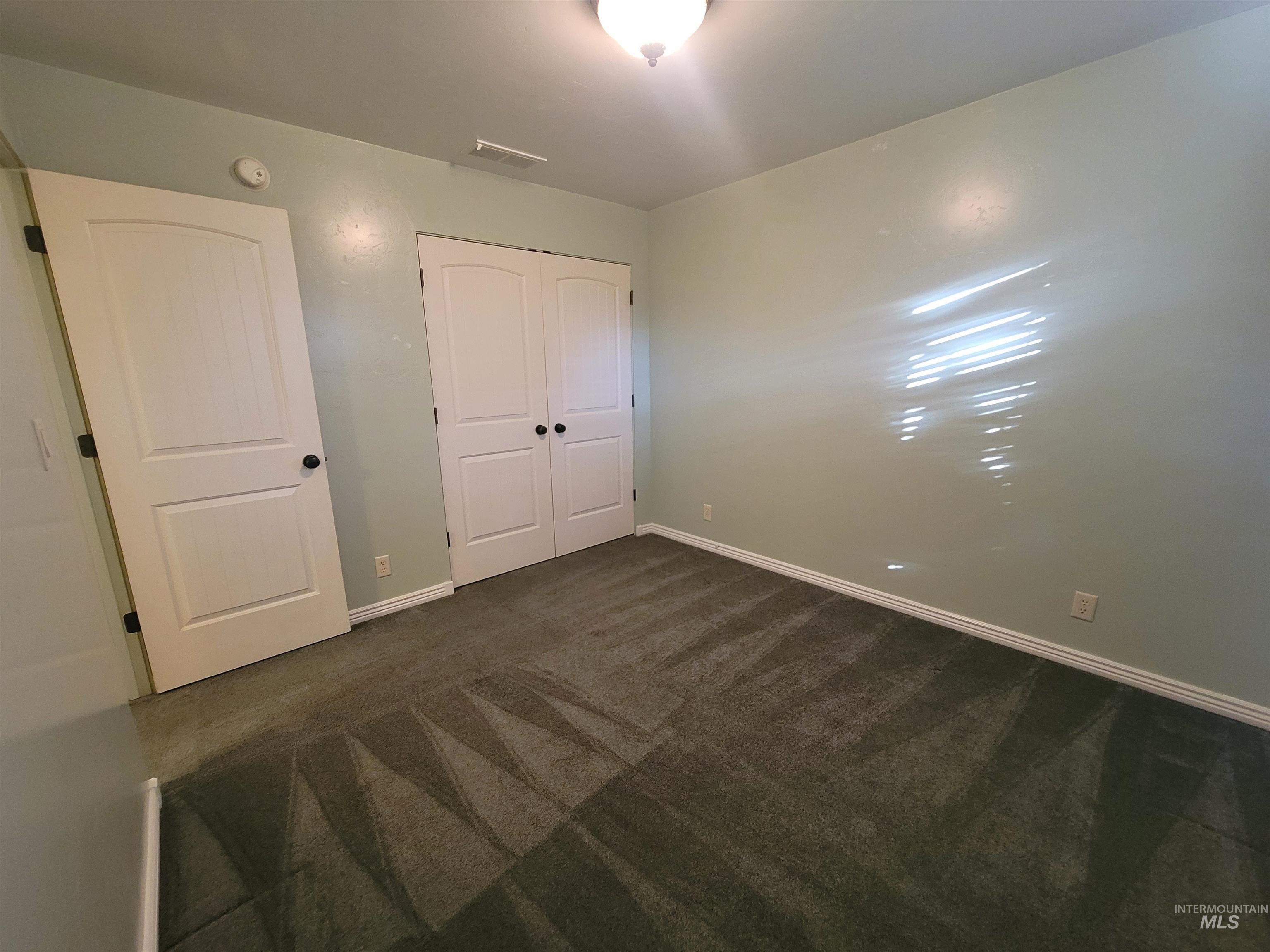 Unfurnished bedroom with dark colored carpet and a closet
